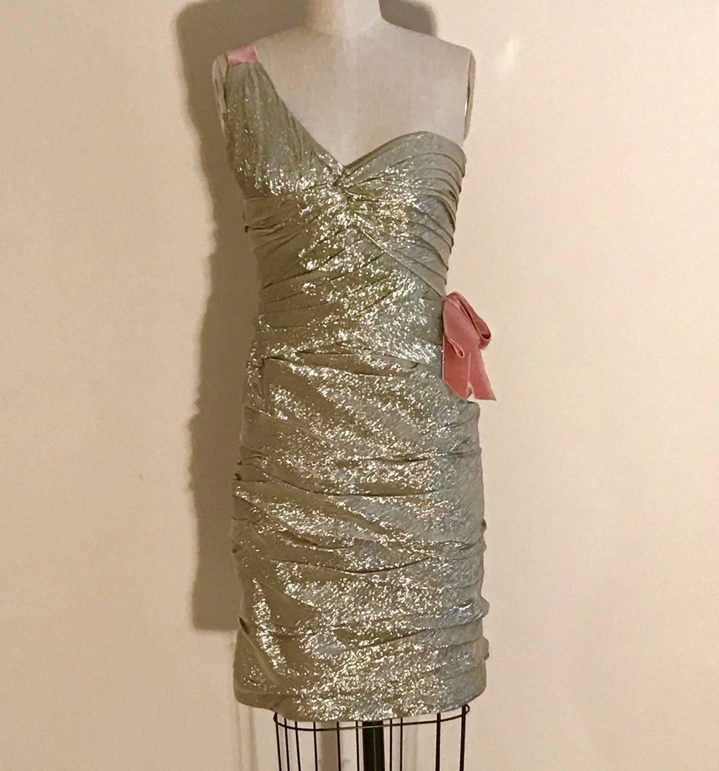 Oscar de la Renta metallic light gold pleated cocktail dress with pink velvet detail at a small side bow and the strap. Built in corseted detail at top. Back zip and hook. 

70% silk, 30% polyester.
Fully lined in 100% silk. 
100% rayon velvet