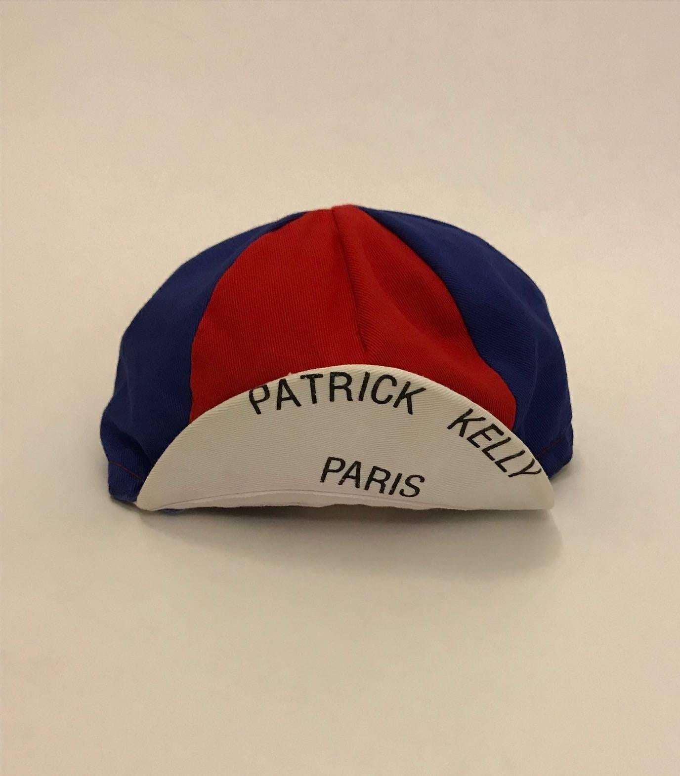 Extremely rare Patrick Kelly 1980's blue, red and white soft elastic back baseball cap with Patrick Kelly Paris printed at the under brim. These iconic 'Paris' printed hats were a piece of Patrick's signature style-- you rarely caught him without