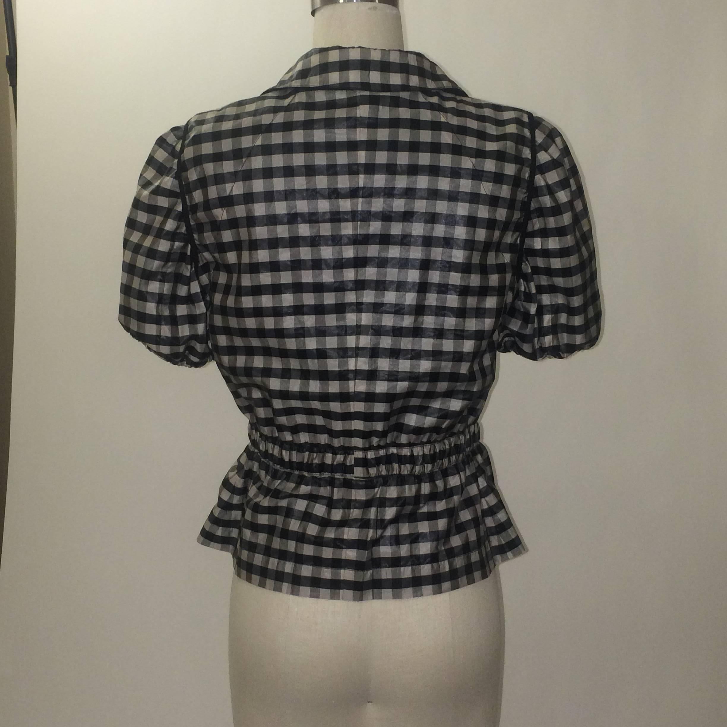 Armani Collezioni short sleeved jacket in a very pale grey and black checked pattern. Elastic at hem of short sleeves. Zips and snaps up front with adjustable hidden elastic at waist. Patch pockets at front bottom. Signed 'Armani Collezioni' at