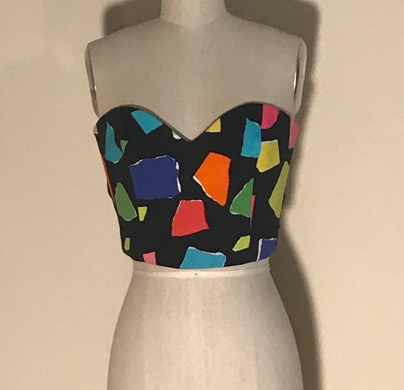 Moschino Couture (designed by by Jeremy Scott) black and multi color abstract print bustier style top with sweetheart neckline and tie back. Boned at front. Fastens at back with cloth covered elastic on hooks, which is then covered with the tie.