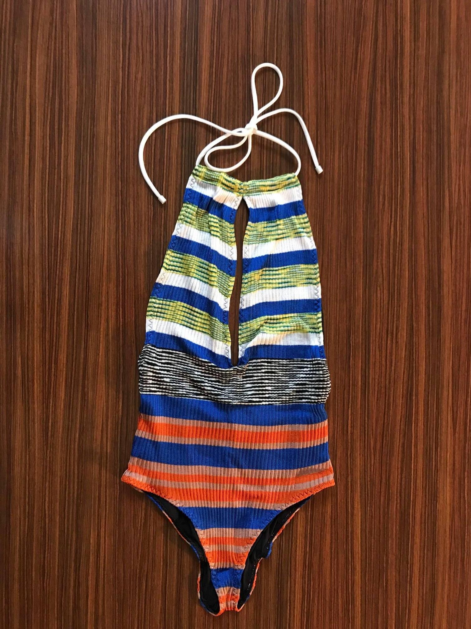 Missoni rib knit one piece bathing suit with multicolor stripes. Deep slit at front, ties at neck. You can slide the front panels around the neck tie, depending on how much you'd like to reveal. Low back with a slight V at bottom. 

Includes blue,