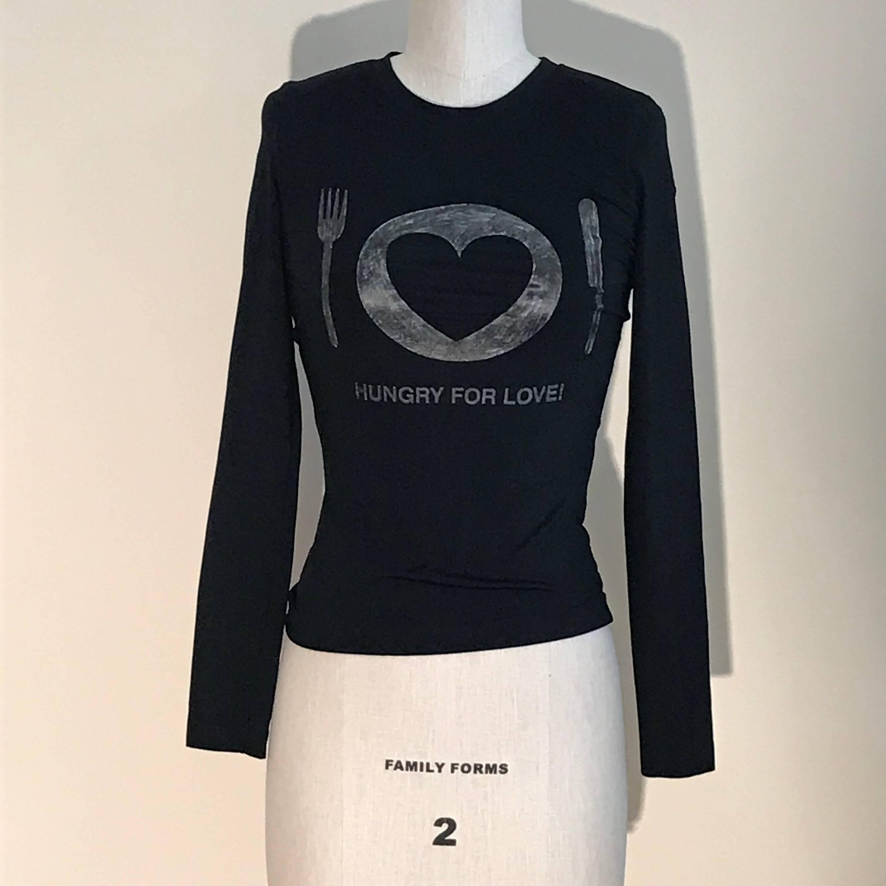 Vintage 1990s Moschino Jeans black Hungry For Love graphic long sleeve t-shirt. Features a table setting with a fork, knife, and a plate with a heart. Somewhat scribbly silvery grey shading at graphic.

78% polyamide, 22% elastane. 

Made in