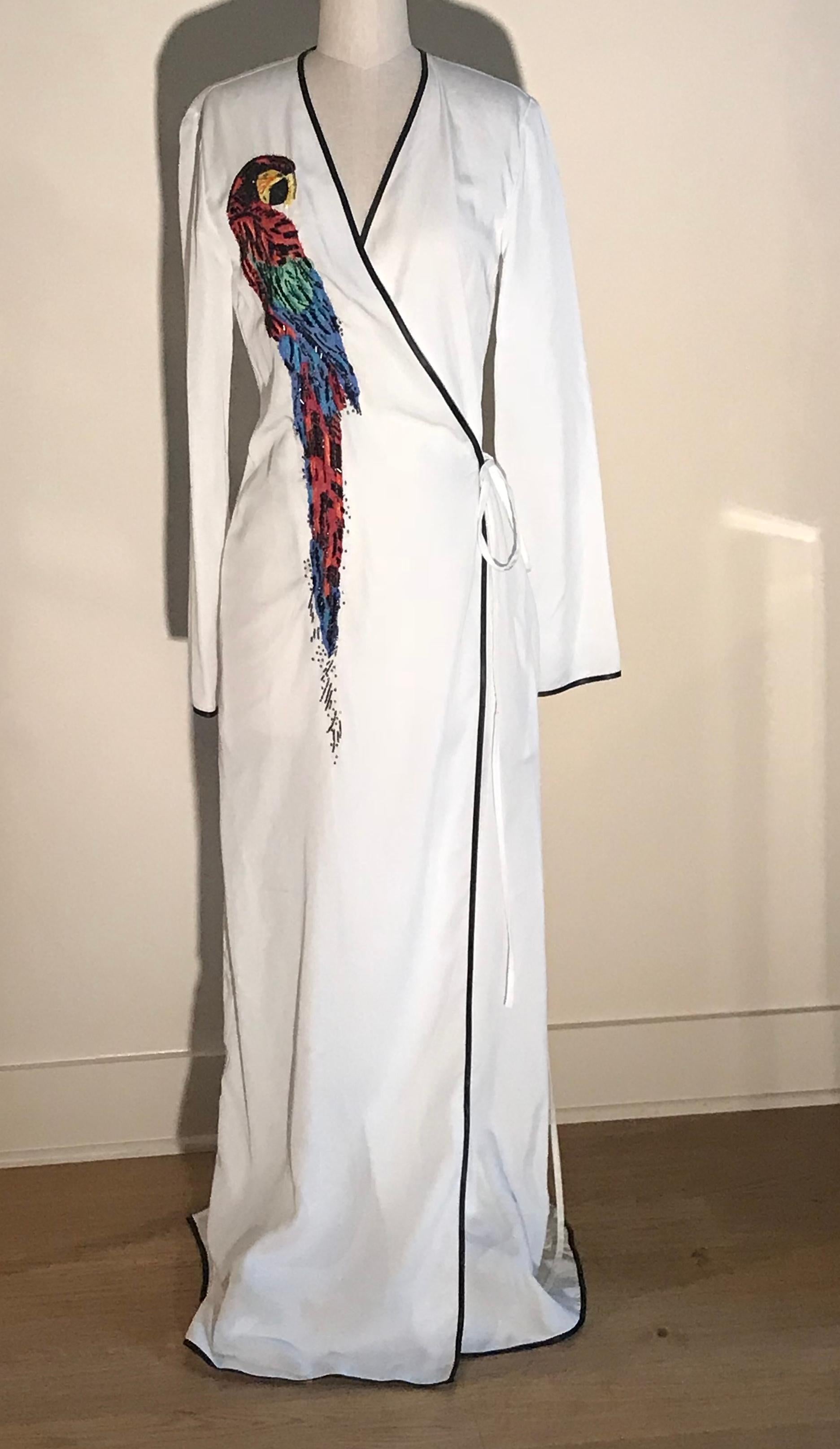 Attico long sleeved wrap dress with embellished parrot design and contrast trim. Large appliqué parrot with raw edges and embroidery and bead detail. Pockets at side seams, attached tie at waist, slit at back center. Looks great styled over a silk