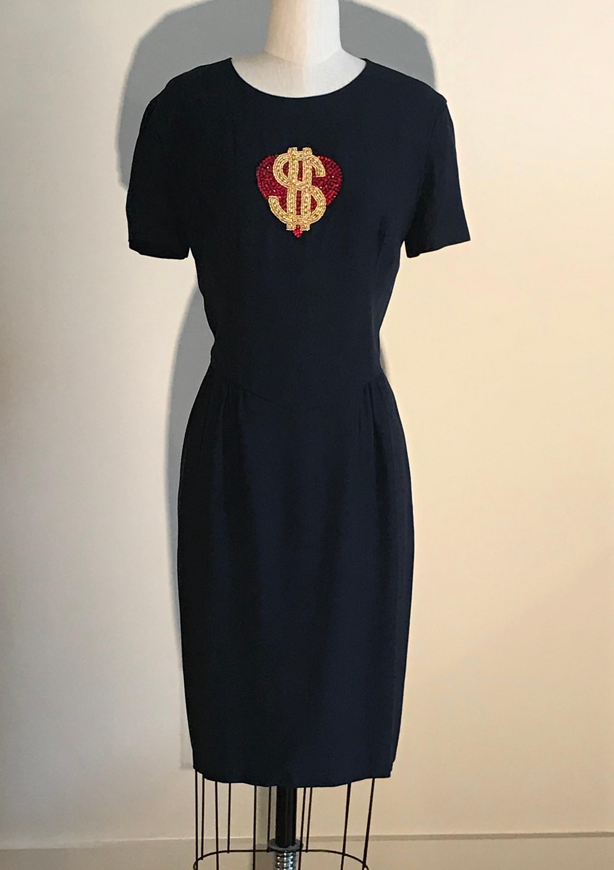 Vintage 1990s Moschino Couture navy blue short sleeved dress with beading at chest forming a red heart and gold dollar sign. Short sleeves, back zip.

55% acetate, 45% rayon.
Fully lined in 60% acetate, 40% rayon.

Made in Italy.

Labelled size IT