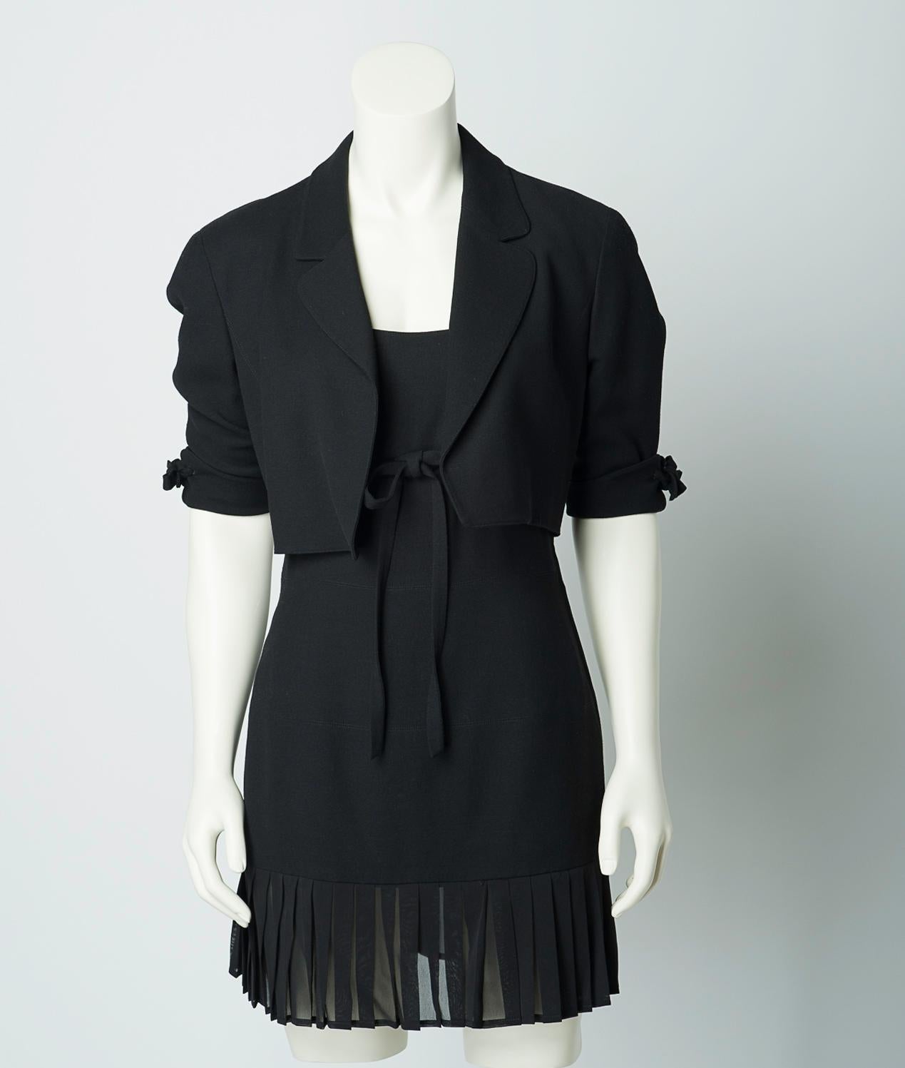 Claude Montana vintage 1980s black mini dress and cropped jacket set. 
Black sleeveless dress features sheer pleated trim and tie detail at empire waist. Open front jacket features tie detail at sleeves.

40% viscose, 40% wool, 20% silk.
Trimmed in