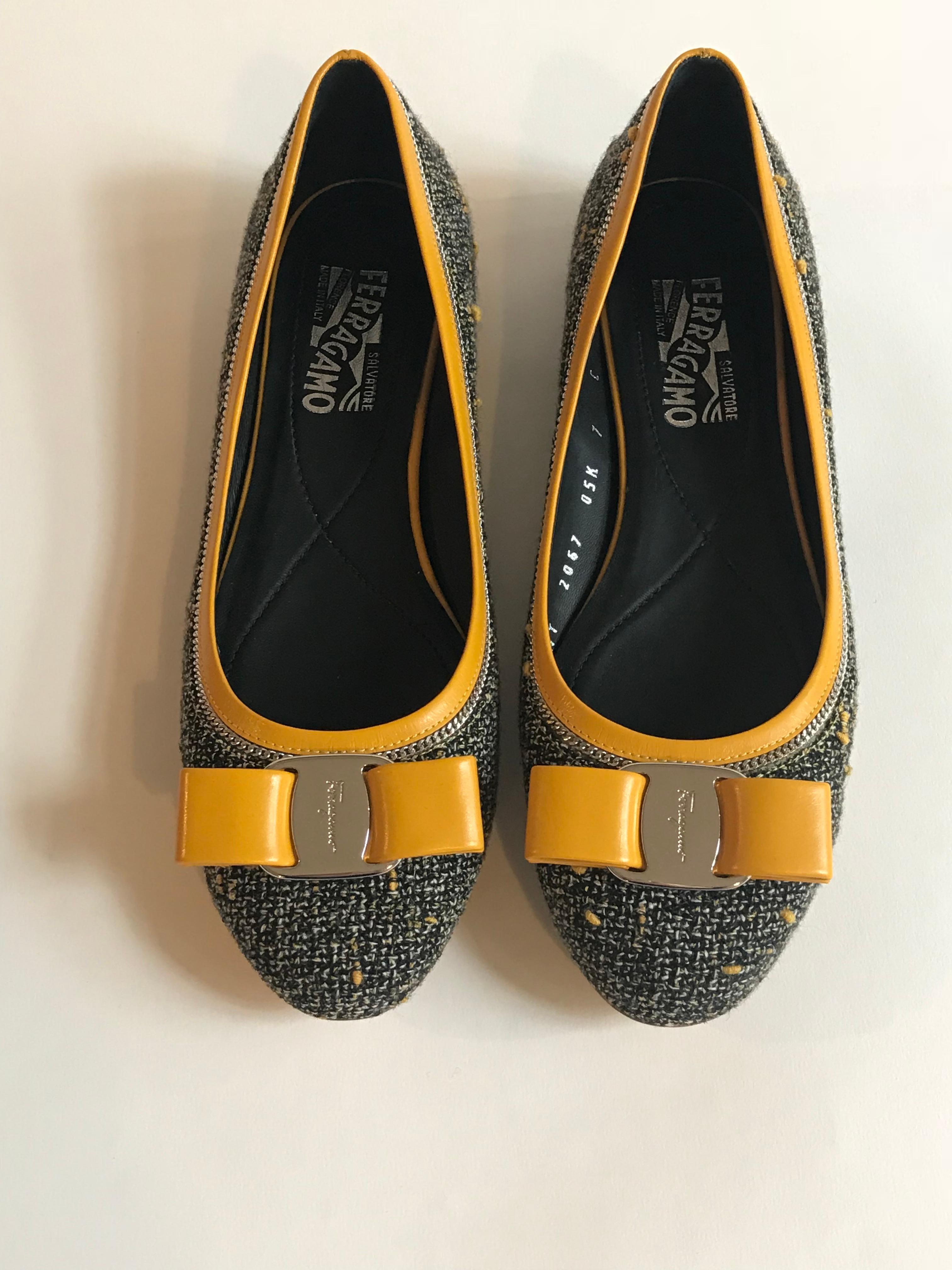 Salvatore Ferragamo black and white tweed shoes with pollen yellow accents. Round toe ballerina flat style. Silver chain and yellow leather detail at upper trim. Yellow leather bow at toe with signature Ferragamo script logo at metal center. 

Made