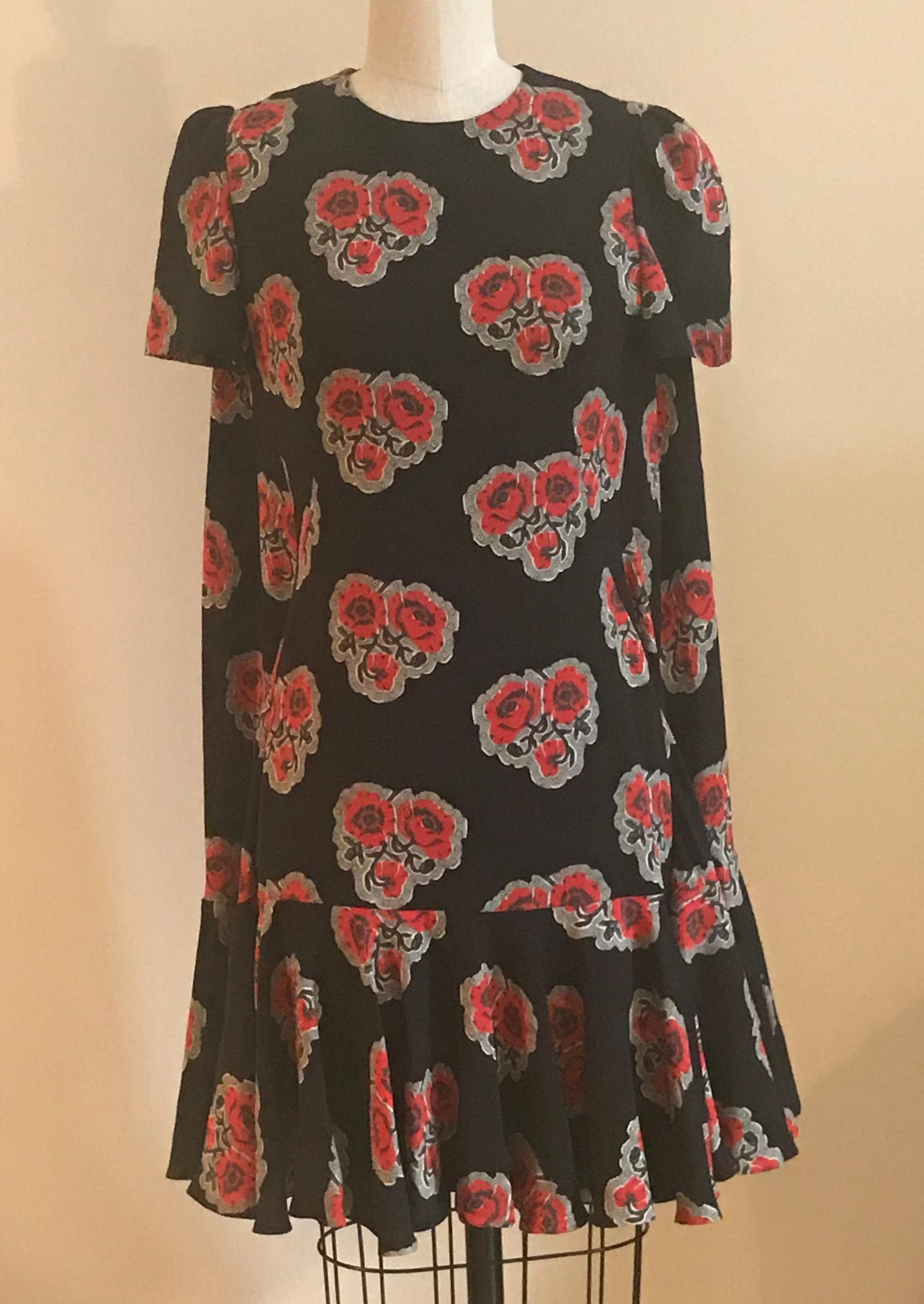 Alexander McQueen black silk crepe dress with red poppy floral print. Sweeping back cape is attached at the side seams. Short sleeve with a wide ruffle hem. Back zip is concealed by cape overlay. Two buttons at back neck. 

Retailed at $3075.

100%
