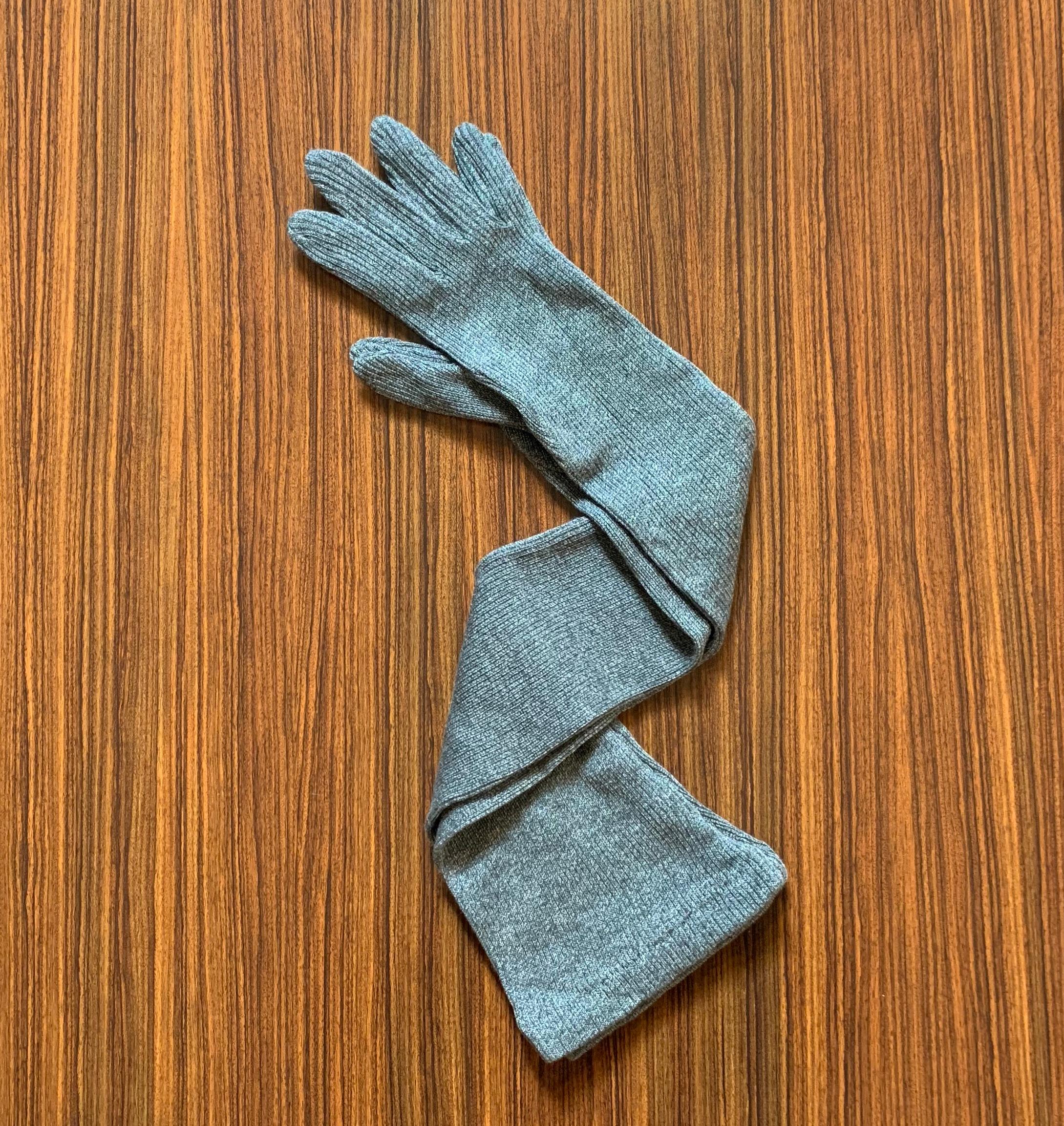 Patrick Kelly vintage 1980s long knit gloves in a soft medium grey rib knit. An iconic runway piece that was purchased at an auction of the pieces remaining from Patrick Kelly's atelier. 

Unsigned. Labelled 'Made in France.'  Auction details can be