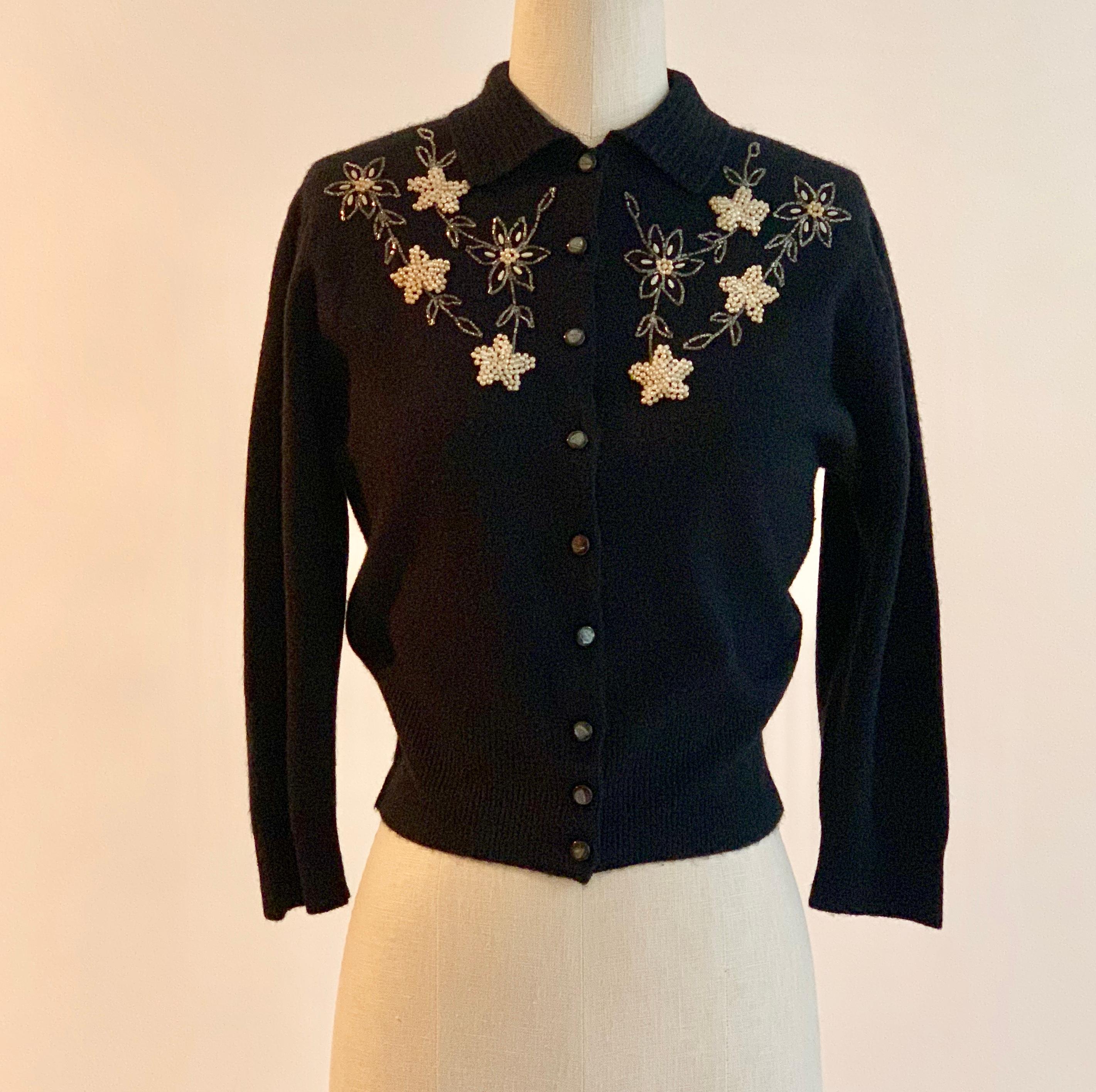 Schiaparelli vintage 1960s black cardigan sweater with rib knit collar and cream floral beading at chest. Slightly cropped length. 

Signed 'Styled by Schiaparelli, Paris' at label. 

No content label, feels like supersoft blend of wool/Angora and