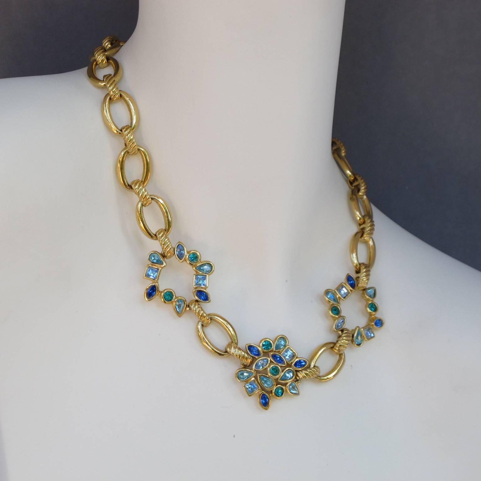 Vintage 1980s Yves Saint Laurent Paris gilt metal necklace with beautiful sparkling, blue-green colored glass rhinestones. Elegant gilt metal chain with metal all pierced and textured ornate with three central floral elements topped with rhinestones