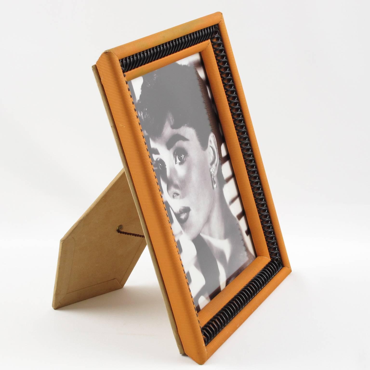 Lovely vintage Mid-Century Modernist picture photo frame. Colorful orange and black plastic raffia with nice geometric carved and see thru design. Easel backing in beige velvet with texture pattern. France, circa 1960s. 

Measurements:
Overall: