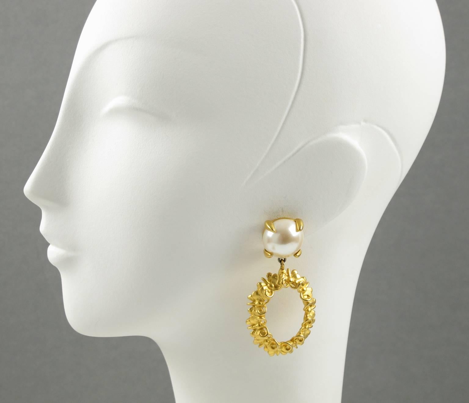 Vintage GIVENCHY Paris signed clip on earrings. Featuring large dangling hoop shape, gilt metal all textured with carved butterfly design and ornate with simulated half pearl. Signed with "Givenchy - Paris - New York" engraved on clip and