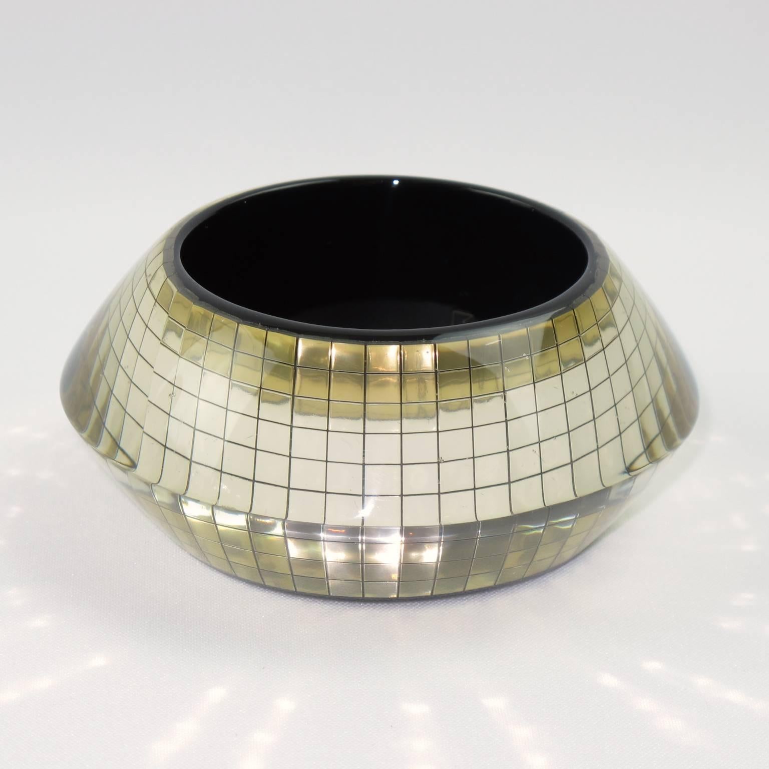 Impressive chunky Space Age Lucite bracelet bangle. Oversized flying saucer crystal clear carved shape with faceted tiny mirrors inclusions and black background. Extremely glittering pattern. France, circa 1960s. Excellent vintage