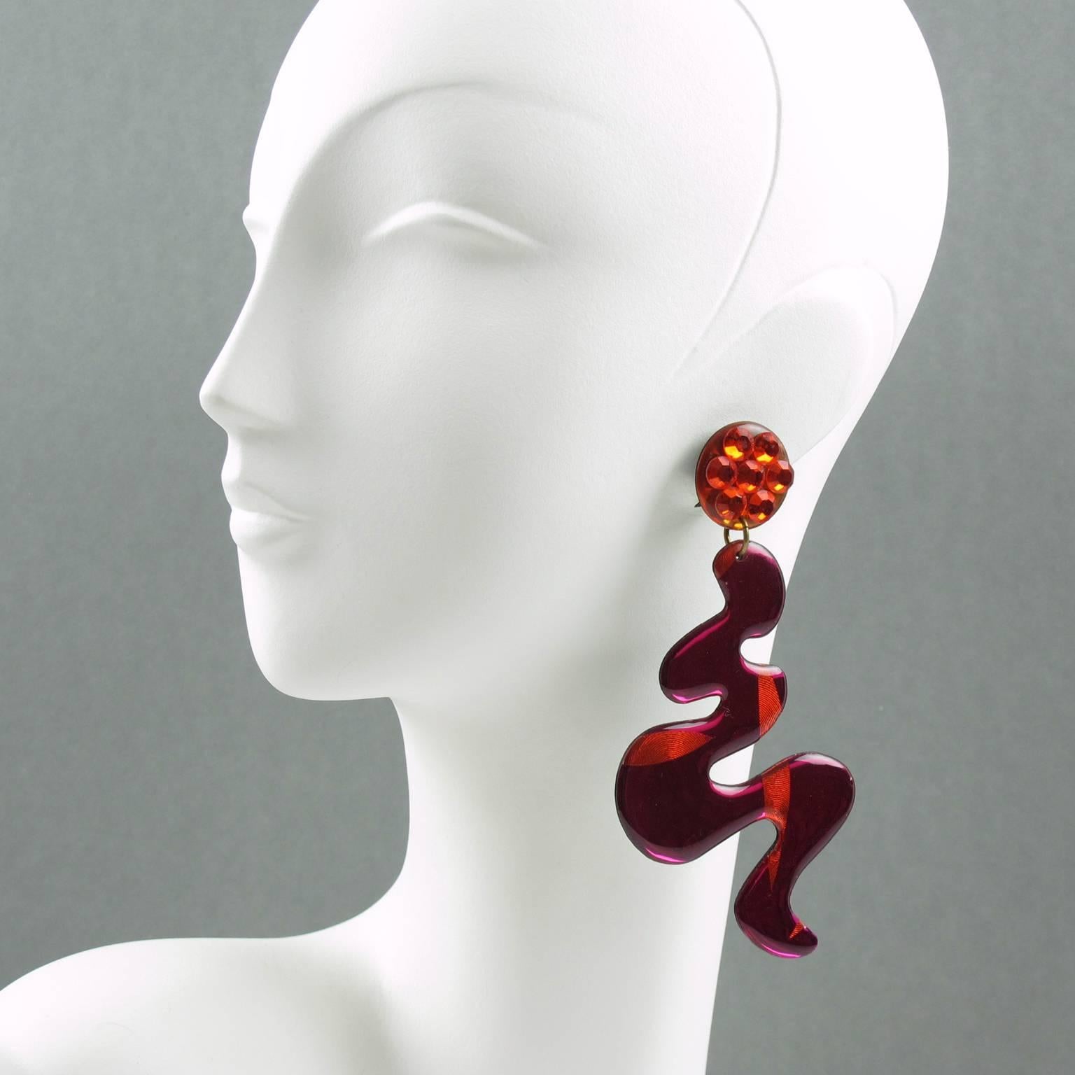Impressive Italian Lucite or Resin dangling clip on earrings. Oversized chandelier shape with free-form design in hot pink and orange colors with texture pattern and black background. Clip fittings all paved with neon orange rhinestones.
Excellent