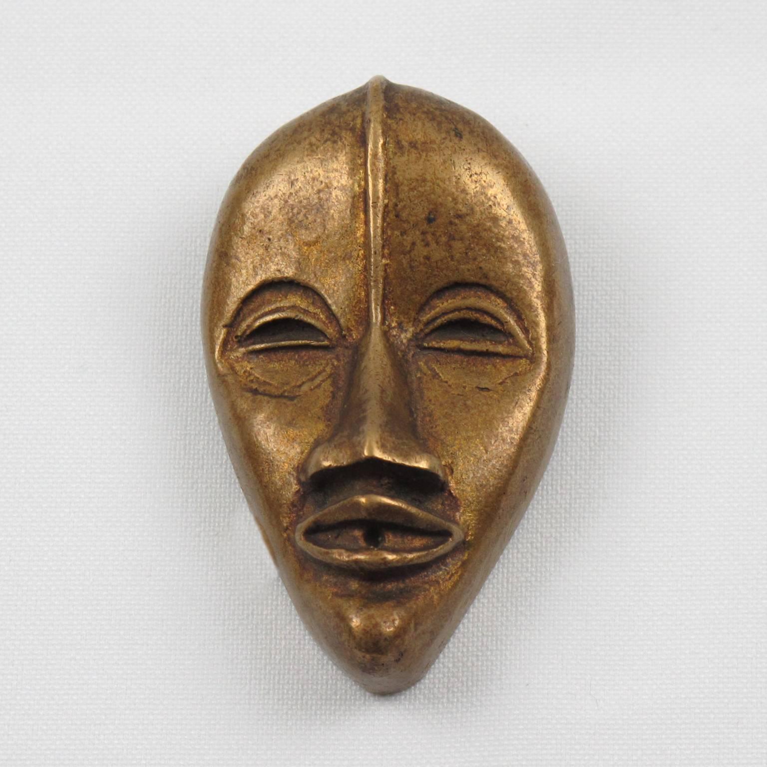 Rare vintage French Art Deco gilded bronze pin brooch dress clip. Featuring an oversized dimensional carved african mask. Folding over dress clip in excellent working condition. No visible marking. France, circa 1930s.

Measurements: 2.50 in. high