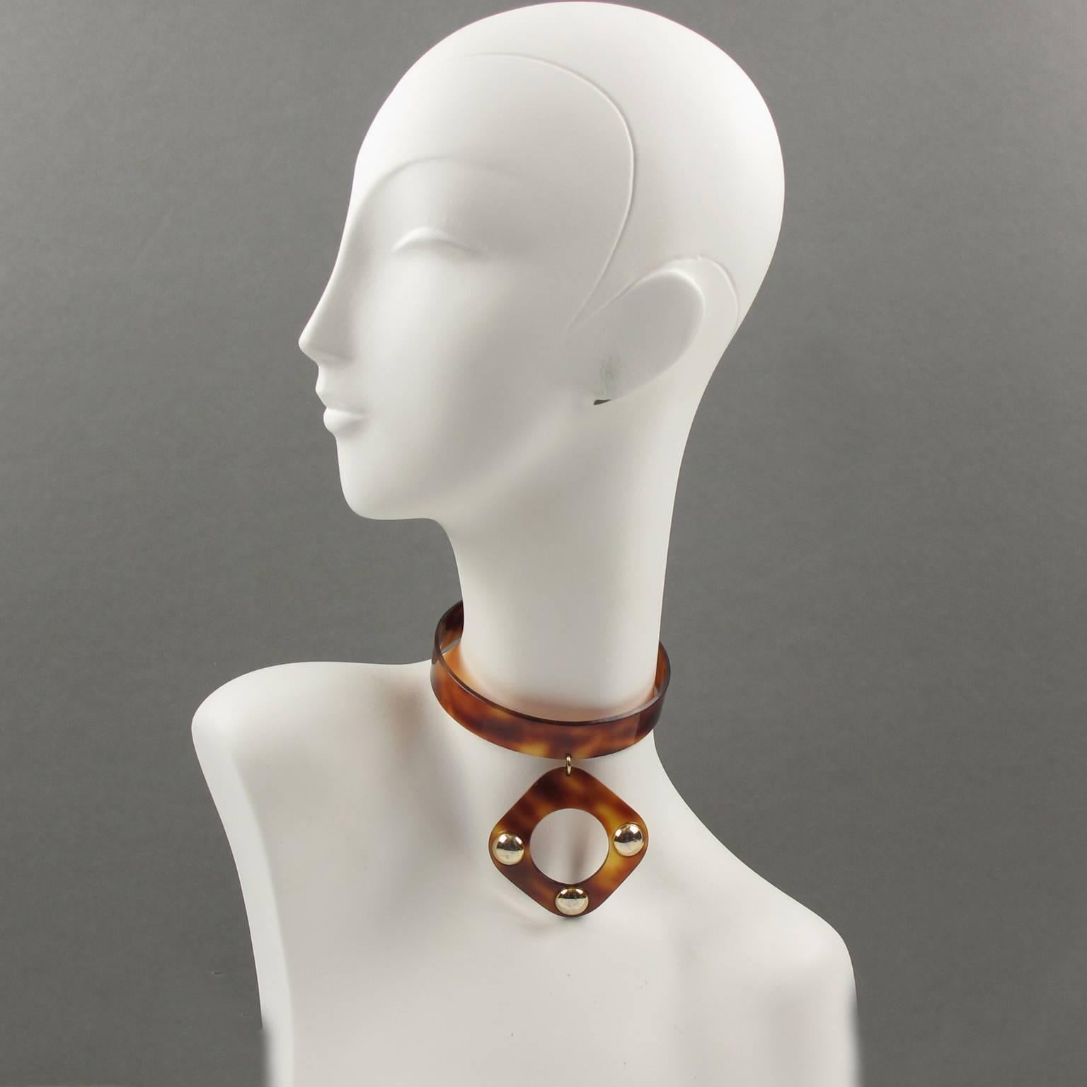 Rare 1970s Space Age celluloid dog collar necklace in the style of Courreges creations. Around the neck modernist rigid band with geometric dangling charm pendant in transparent tortoiseshell color, ornate with gilded metal studs. No marking.
