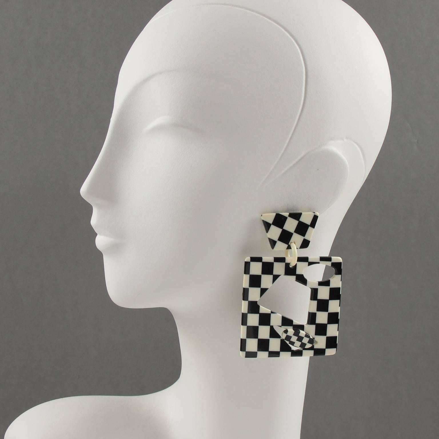 Stunning and rare vintage 1960s Pop Art design Clip on earrings. Featuring oversized dimensional dangling geometric design, (made of Acetate or Celluloid), carved and see thru with gorgeous checkerboard laminated pattern in black and off-white
