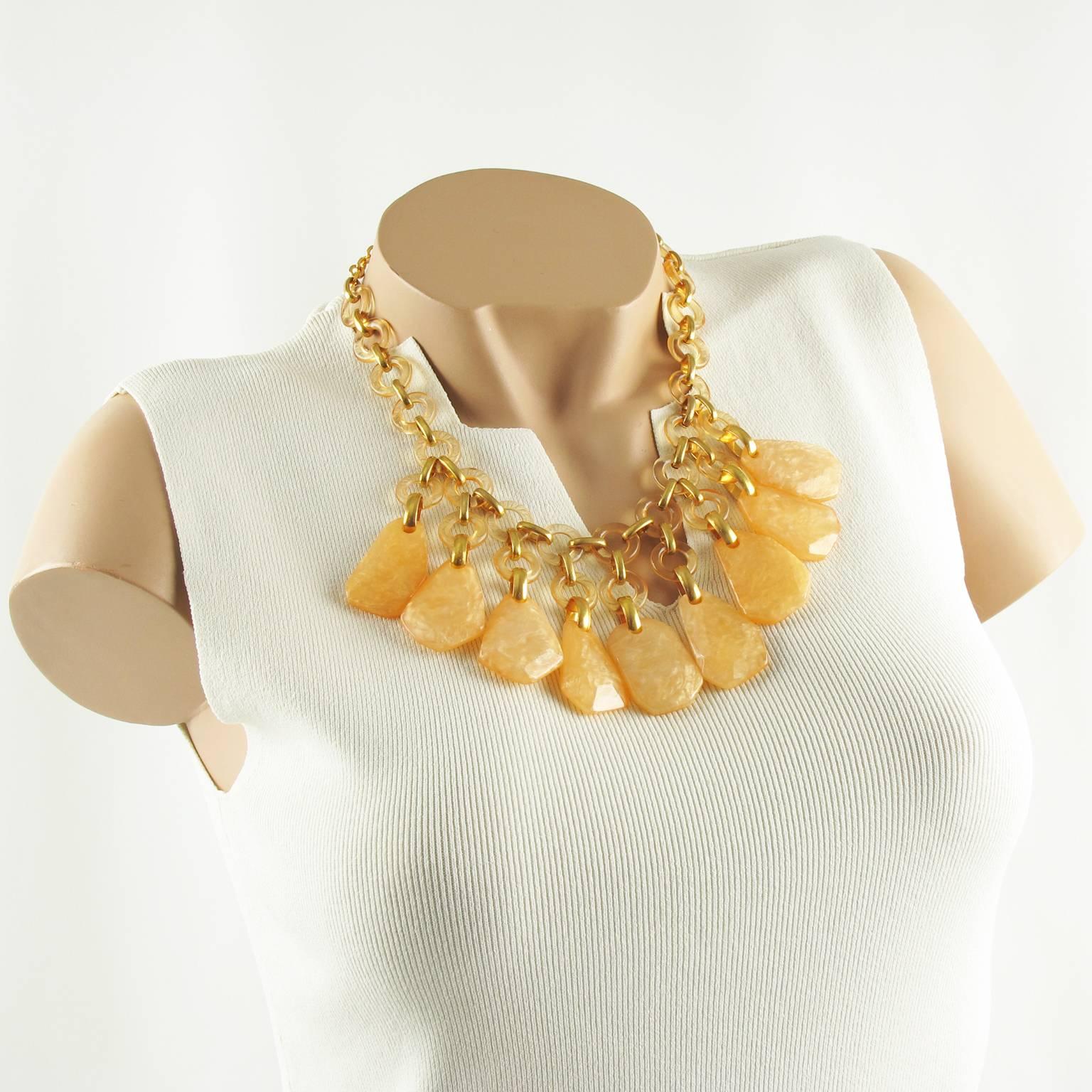 Ravissant collier ras de cou signé Dominique Denaive Paris. Design/One romantique avec chaîne en résine et métal doré ornée de galets en résine texturée. Couleur chaude abricot orange perlé. Fermoir en forme de homard avec chaîne supplémentaire en