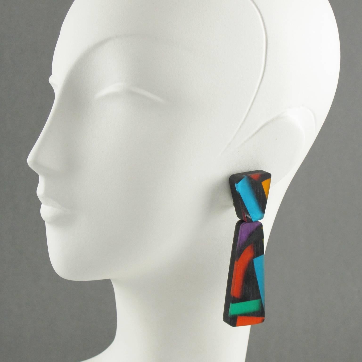 Spectacular and colorful oversized Lucite chandelier clip on earrings designed by Harriet Bauknight for Kaso. Large dangling shape with geometric design featuring dimensional multilayers black lucite with colorful harlequin pearlized inclusions.