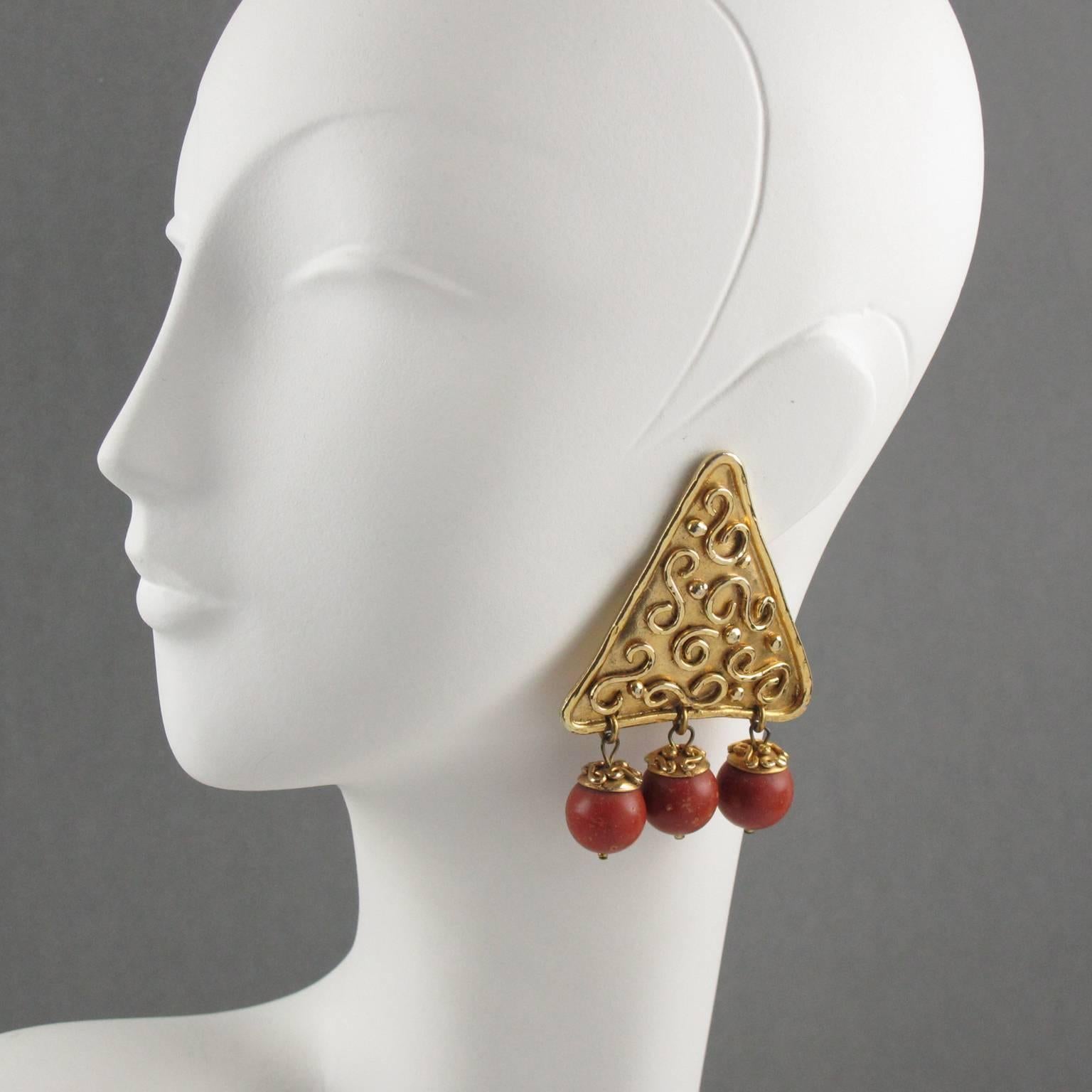 Stunning French designer Edouard Rambaud Paris signed clip on earrings. Oversized Byzantine inspired design with shinny gilded metal large triangle shape all textured and ornate, compliment with dangling resin beads imitating wood. Signed underside