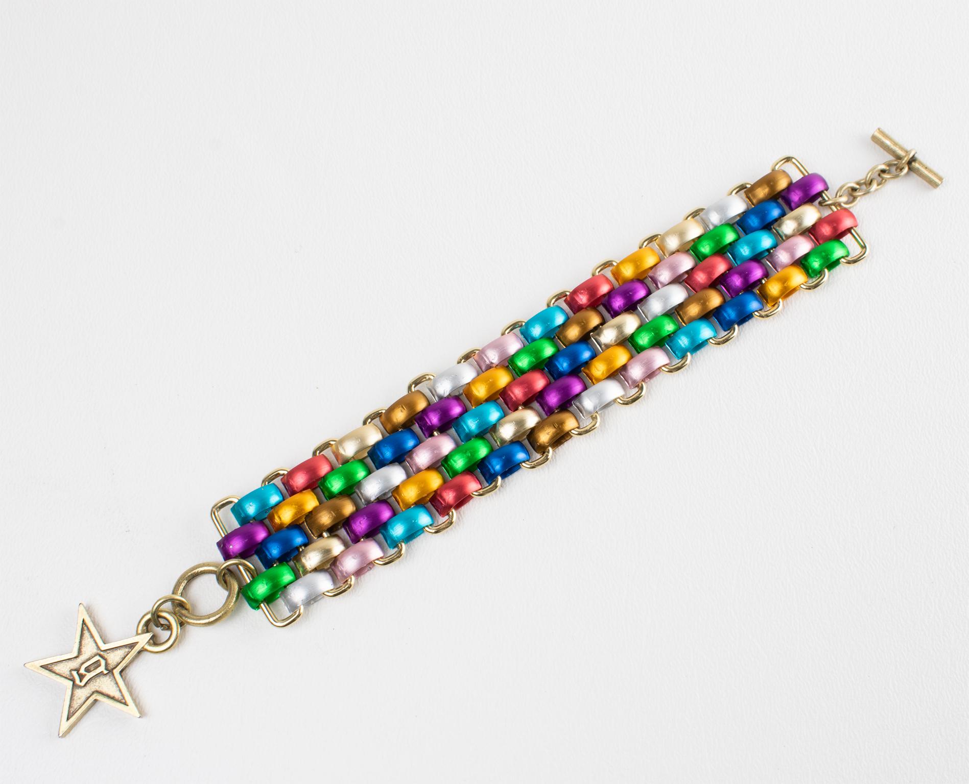 Questo raro braccialetto bangle di John Galliano presenta una forma a maglie grosse in alluminio con un motivo multicolore. Il bracciale è completamente articolato e si adatta molto bene al polso. La chiusura è ad alamaro con il logo Galliano 