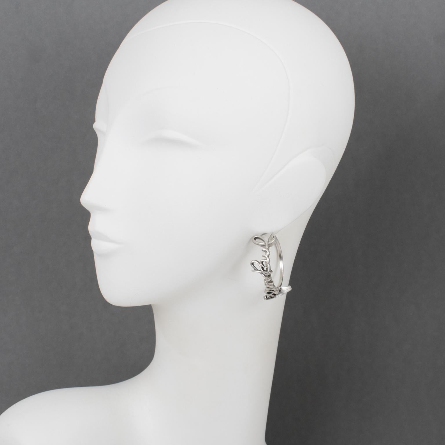 Diese atemberaubenden Ohrringe von Jean Paul Gaultier Paris stammen aus der Ready-to-wear-Laufstegkollektion Frühjahr 2013. Die Ohrringe bestehen aus einem silberfarbenen Ring mit der kursiven Signatur 