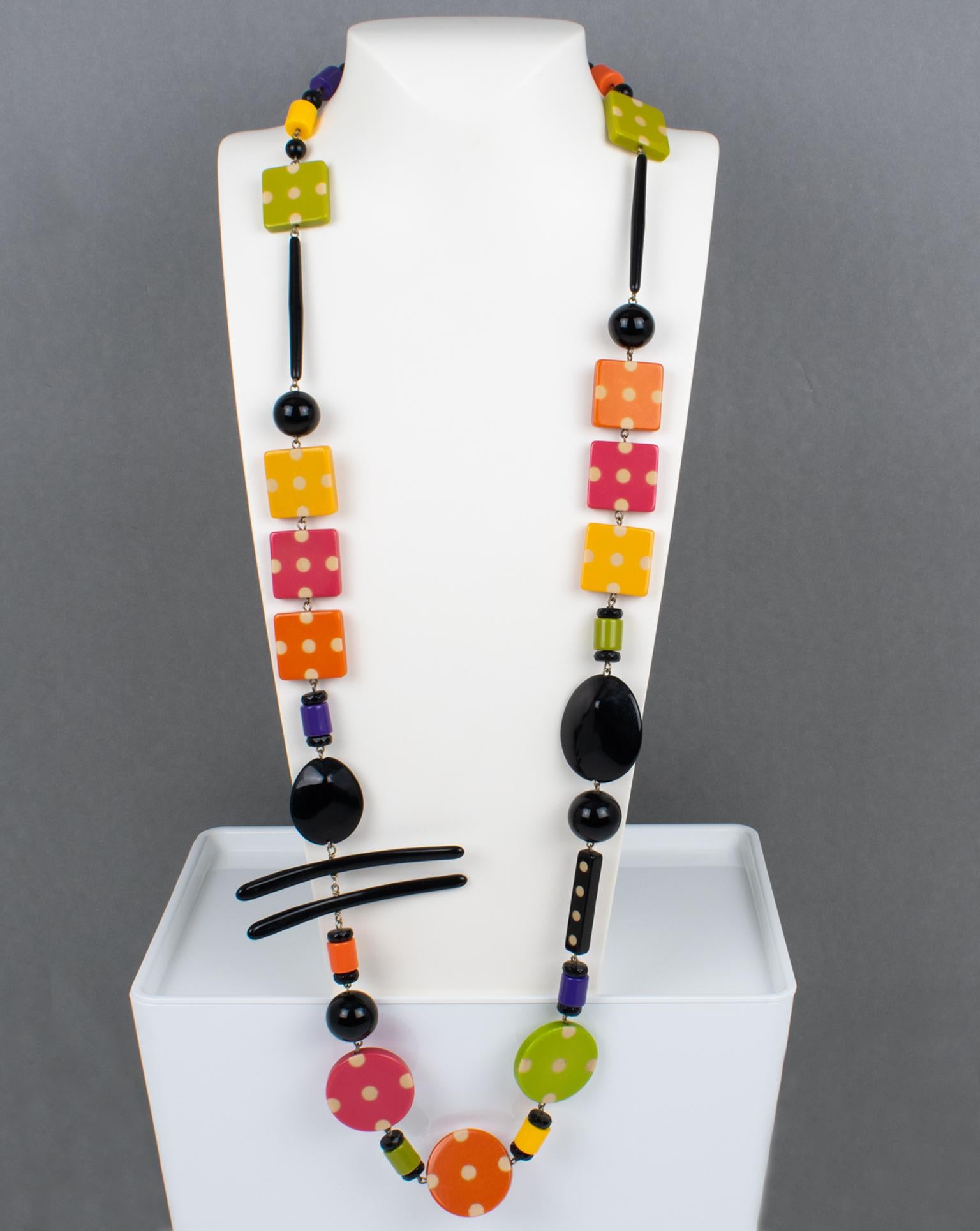 Ce magnifique collier extra-long Angela Caputi, fabriqué en Italie, en résine et Lucite, présente un design ludique. La pièce présente des éléments géométriques dans un motif multicolore avec des textures et différentes formes de perles. Le design