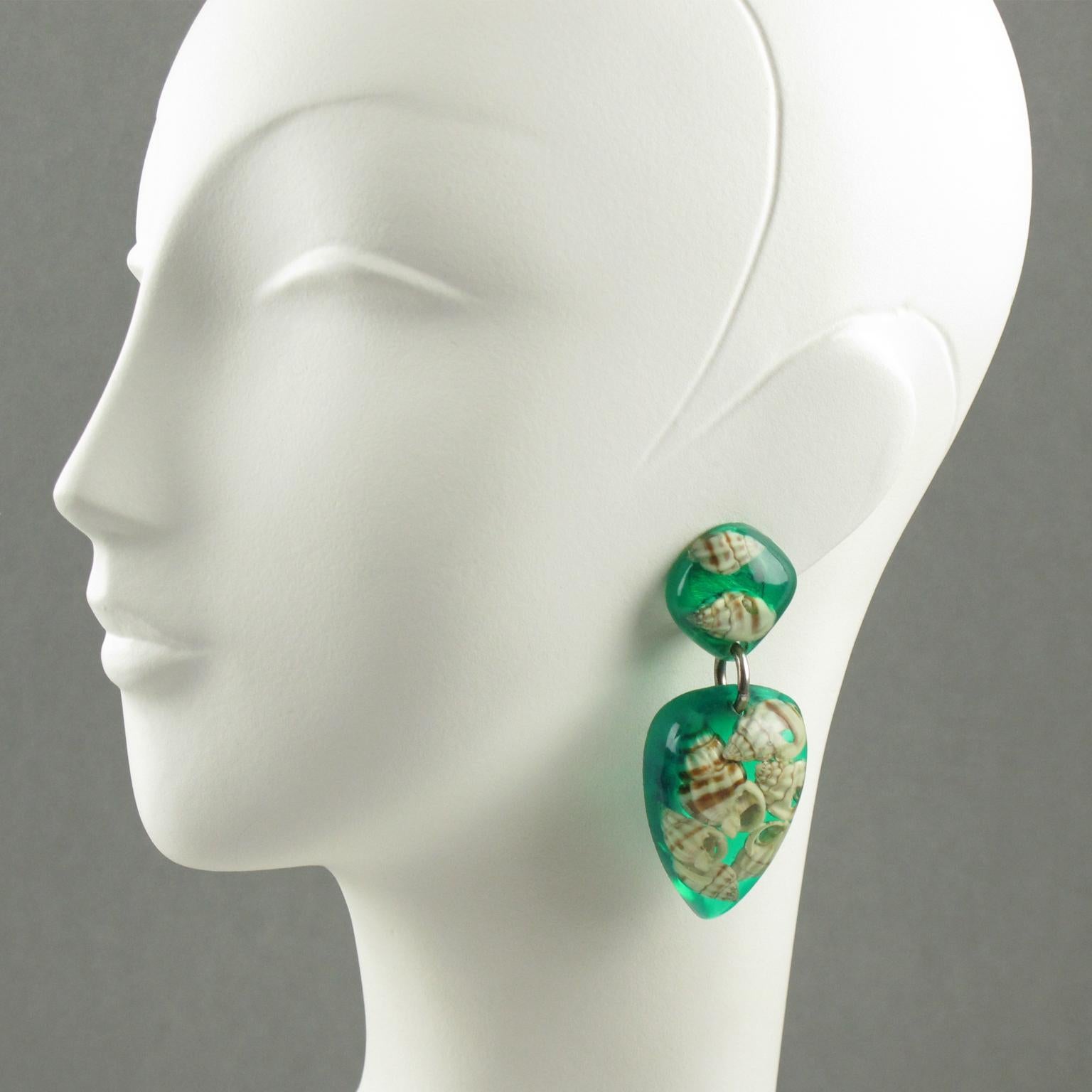 Lovely French oversized Lucite clip on earrings. Elegant long dangling shape with transparent aqua green Lucite and real sea shell inclusions. 
Measurements: 2.82 in. long (7.2 cm) x 1.13 in. wide (2.9 cm)