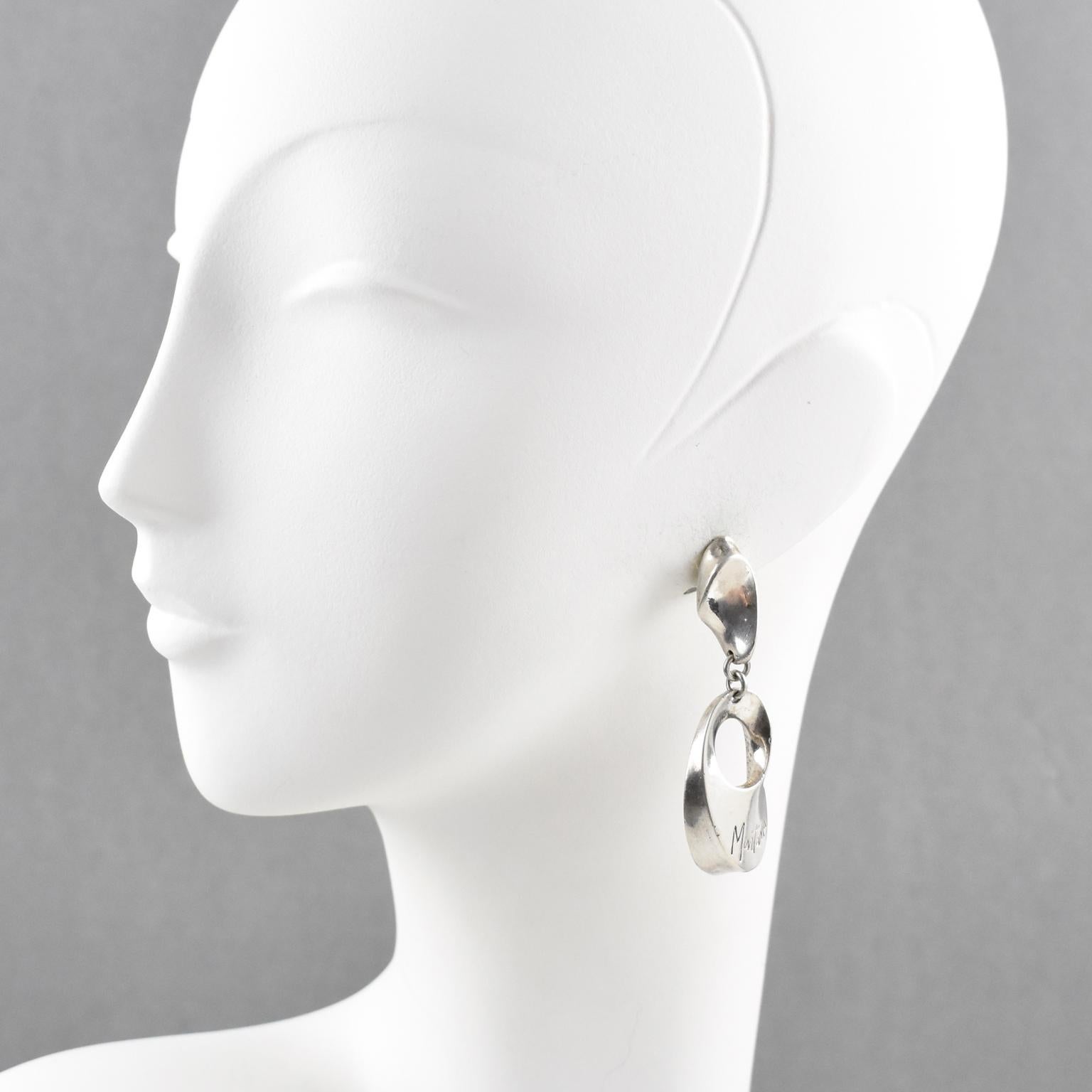 Modernist geometric clip on earrings designed by Claude Montana. Silver plate dangling shape with twisted and pierced elements. Engraved 'Montana' on front.
Measurements: 2.57 in. high (6.5 cm) x 0.82 in. wide (2.1 cm)
Check our storefront or with