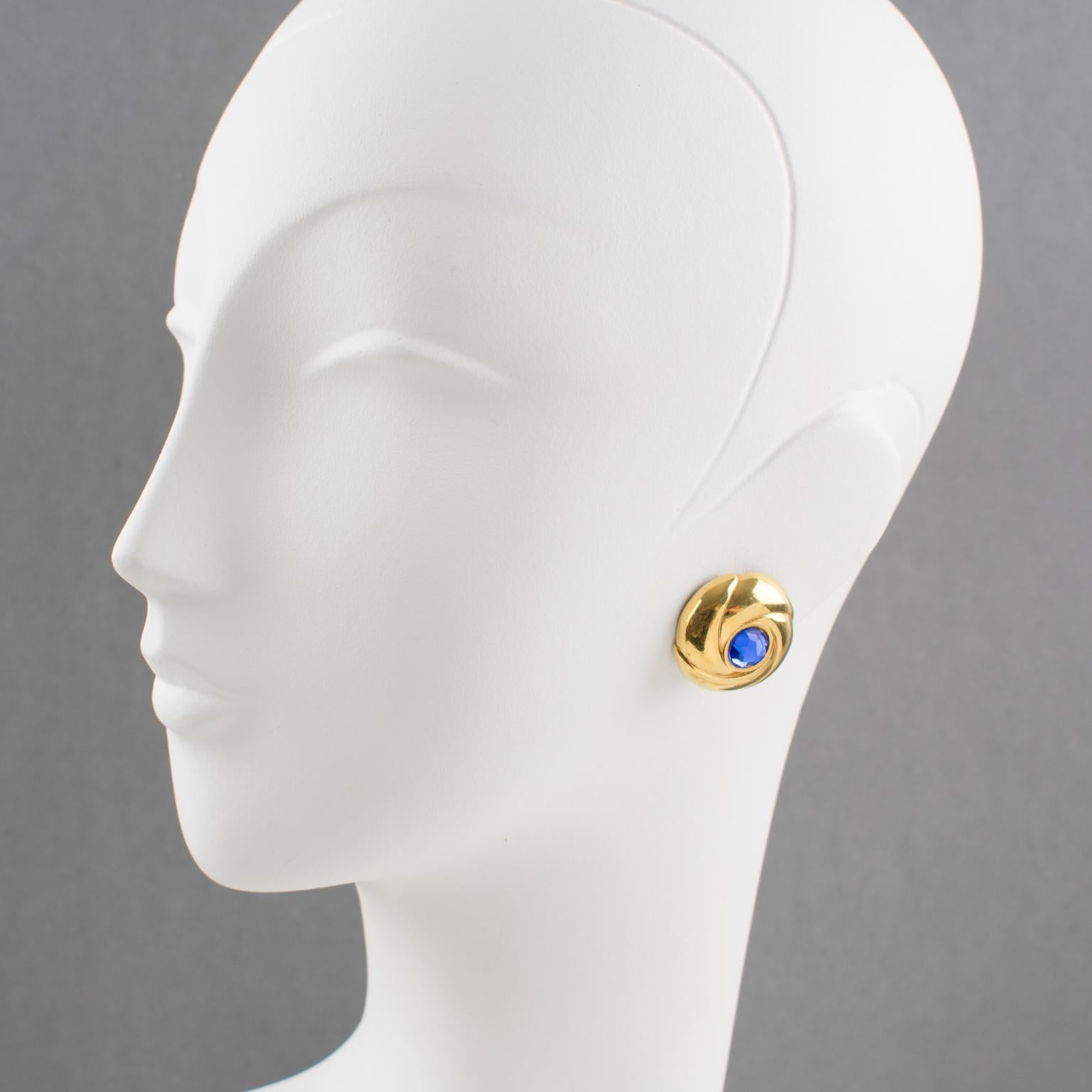 Elegant Courreges Paris clip-on earrings. Dimensional gilt metal round shape, metal all textured and carved, compliment with cobalt blue crystal rhinestone. Signed underside with Courreges Brand logo. 
Measurements: 1 in. diameter (2.5 cm)