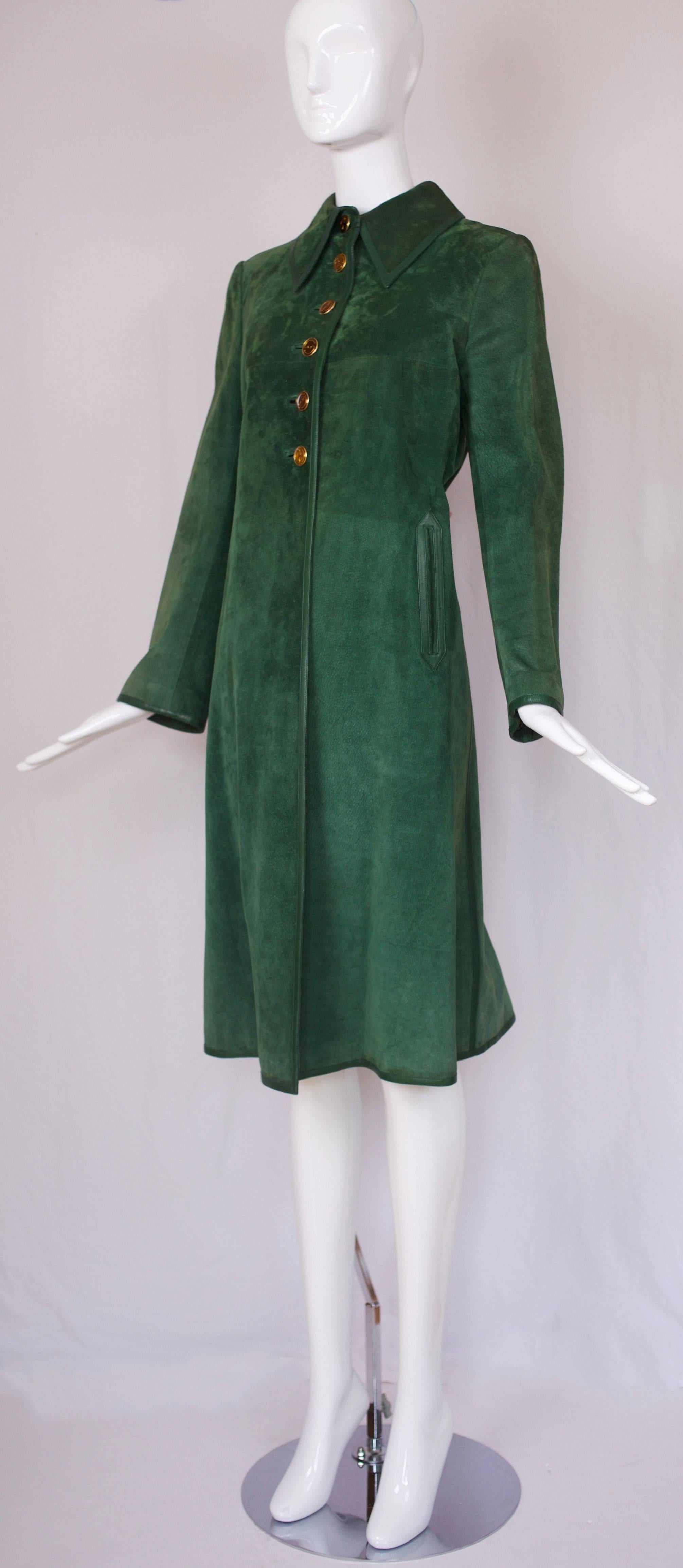 1970's Gucci forrest green suede coat with matching leather trim, two frontal leather trimmed pockets, glazed Gucci GG logo buttons, Gucci logo fabric-lined interior and dart at the center front back that creates folds. In excellent condition with