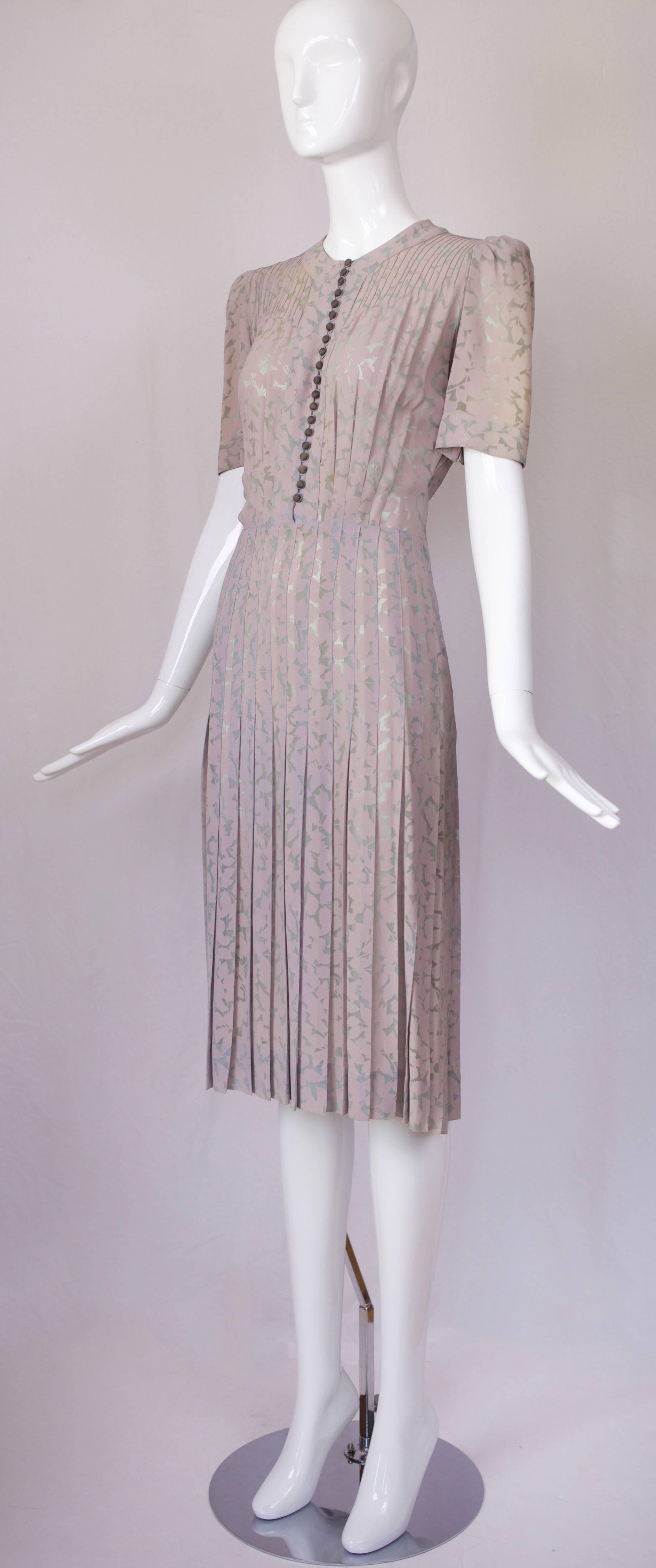 Rare Jeanne Lanvin Adaptation floral print voided crepe day dress circa 1939. The print is in a shadow leaf pattern of pale lavender on green with a pin-tucked bodice top, shoulder with subtle shoulder pads and fabric-covered button closure with