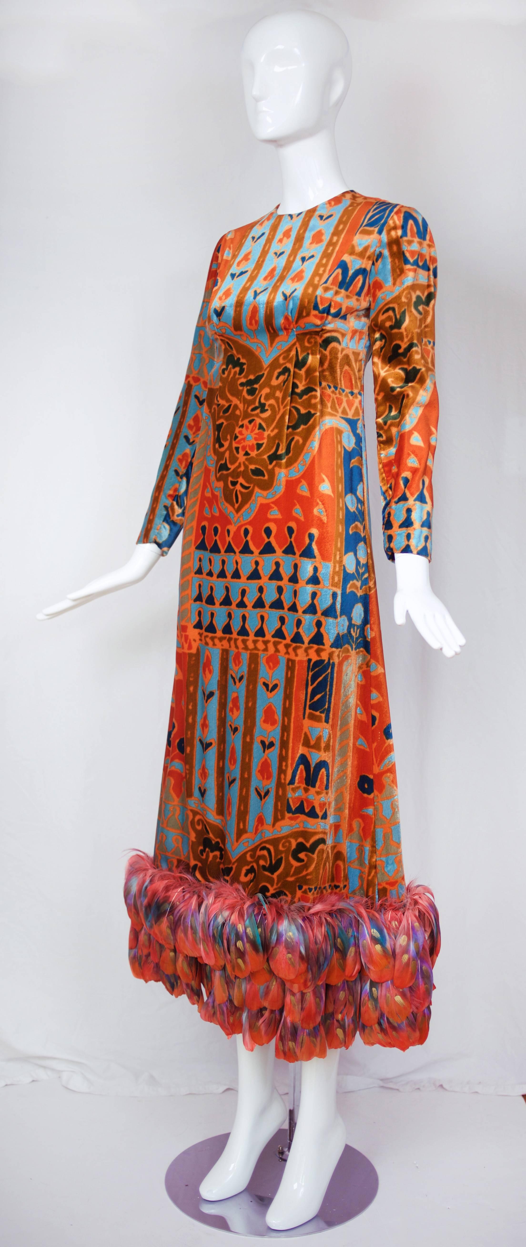 Circa 1970 Bill Blass velvet panne evening gown with Moorish-inspired print in shades of burnt orange, brown, aqua and teal. Structured with pleats through bodice and waistline that turn into a sharp A-line maxi skirt with the hem embellished with
