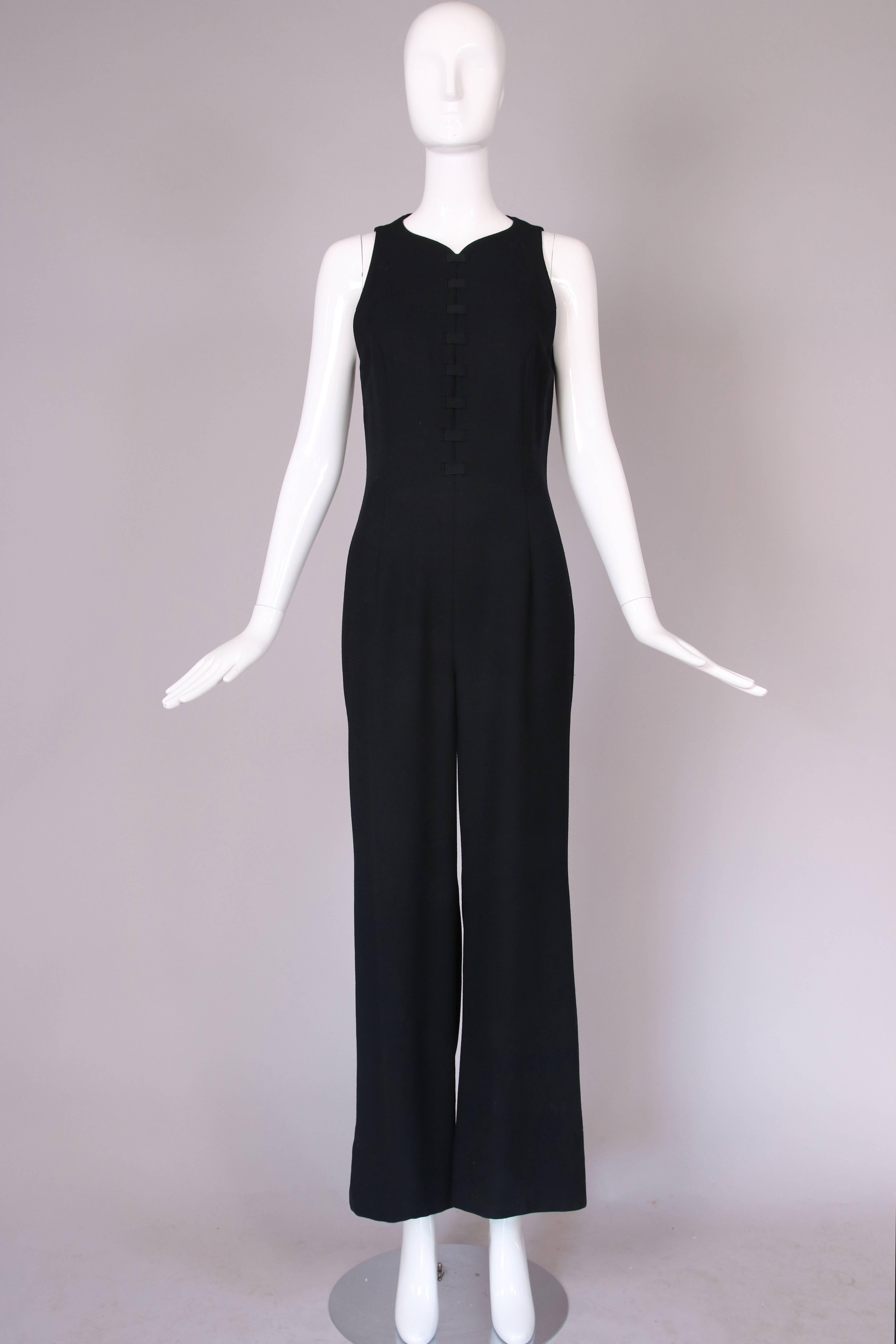 Schwarzer Wollpullover von Versace mit rosafarbener Schleife am oberen Rücken. Rückenausschnitt und kreuzförmiger Verschluss auf der Vorderseite. In gutem Vintage-Zustand mit winzigem, nicht wahrnehmbarem Loch am hinteren
