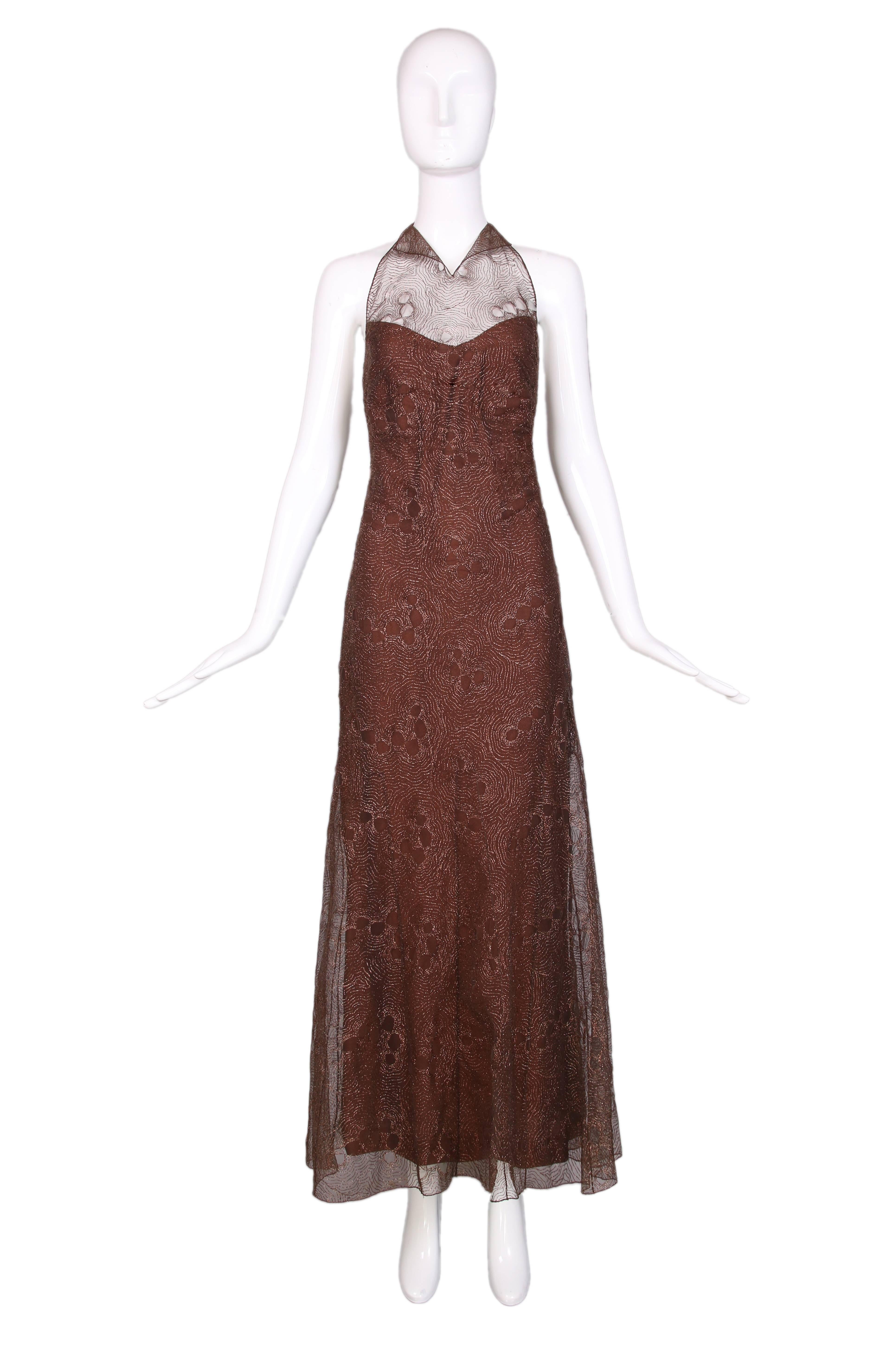 1999 Chanel bronze evening gown featuring tulle overlay embroidered with bronze metallic thread in a floral pattern. Under layer has a sweetheart neckline and low back with zipper closure featuring decorative small, bronze Chanel logo buttons. In