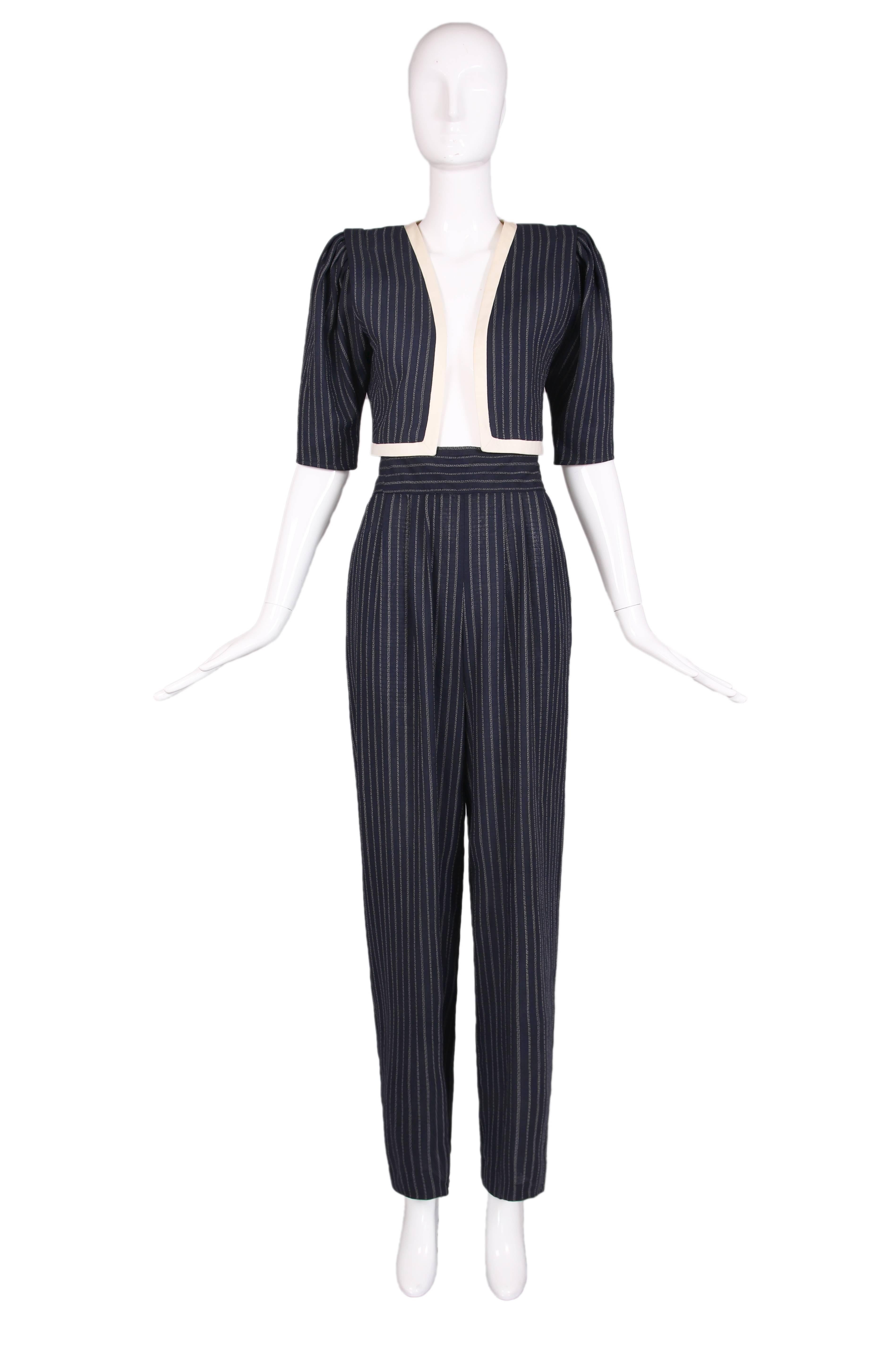 Vintage Emanuel Ungaro navy blue pinstriped crepe two piece ensemble. Fitted cropped jacket has cream colored trim and no closures. High-waisted trouser pants have two side pockets, pleating, and waistband with horizontal pinstripes. In excellent