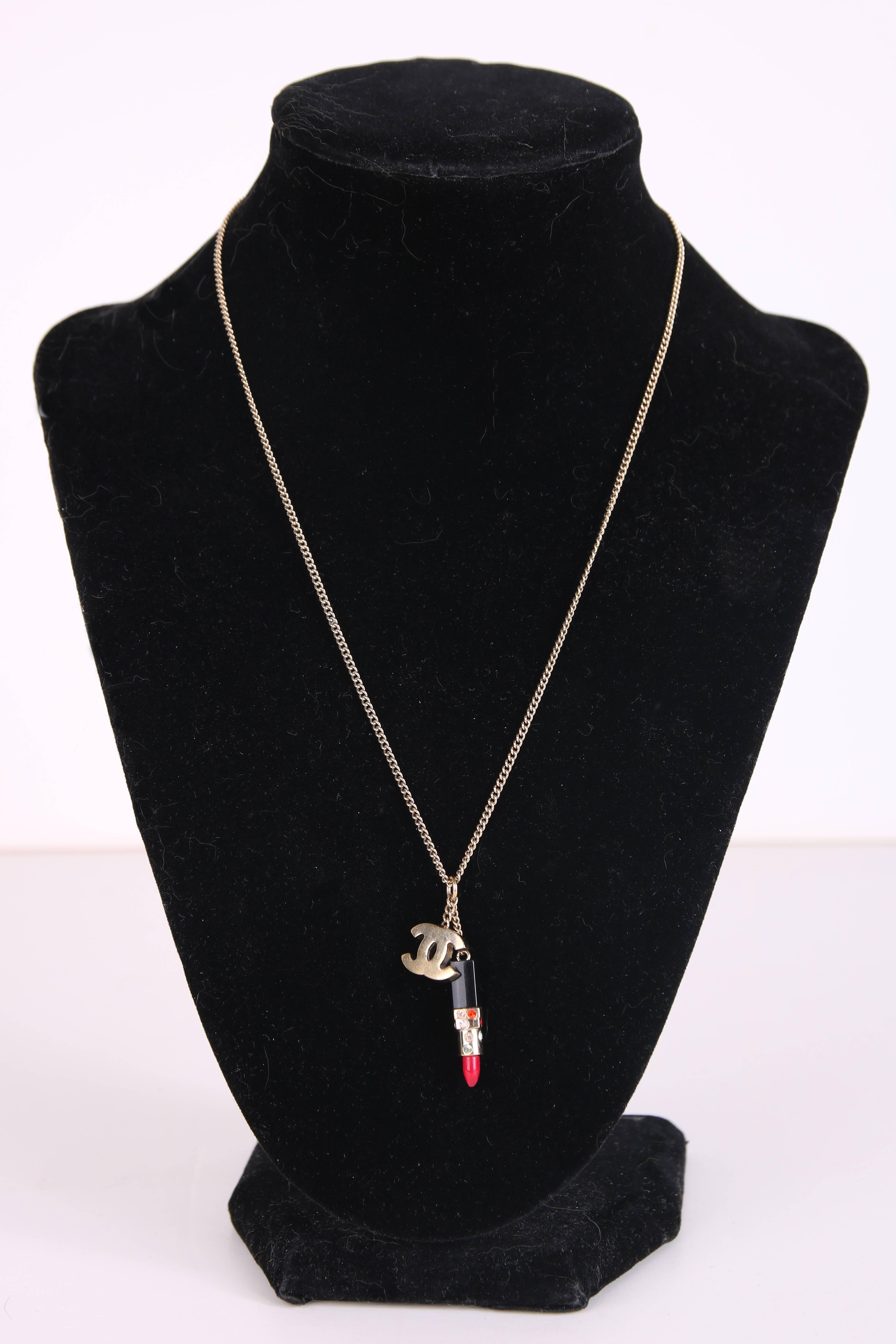 2004A Chanel charm necklace featuring two small charms attached by chain to a jump ring - a red rhinestone encrusted lipstick & gold tone CC logo. Necklace is in excellent condition. Clasp is stamped "04 A."
Measurements:
Chain drop -