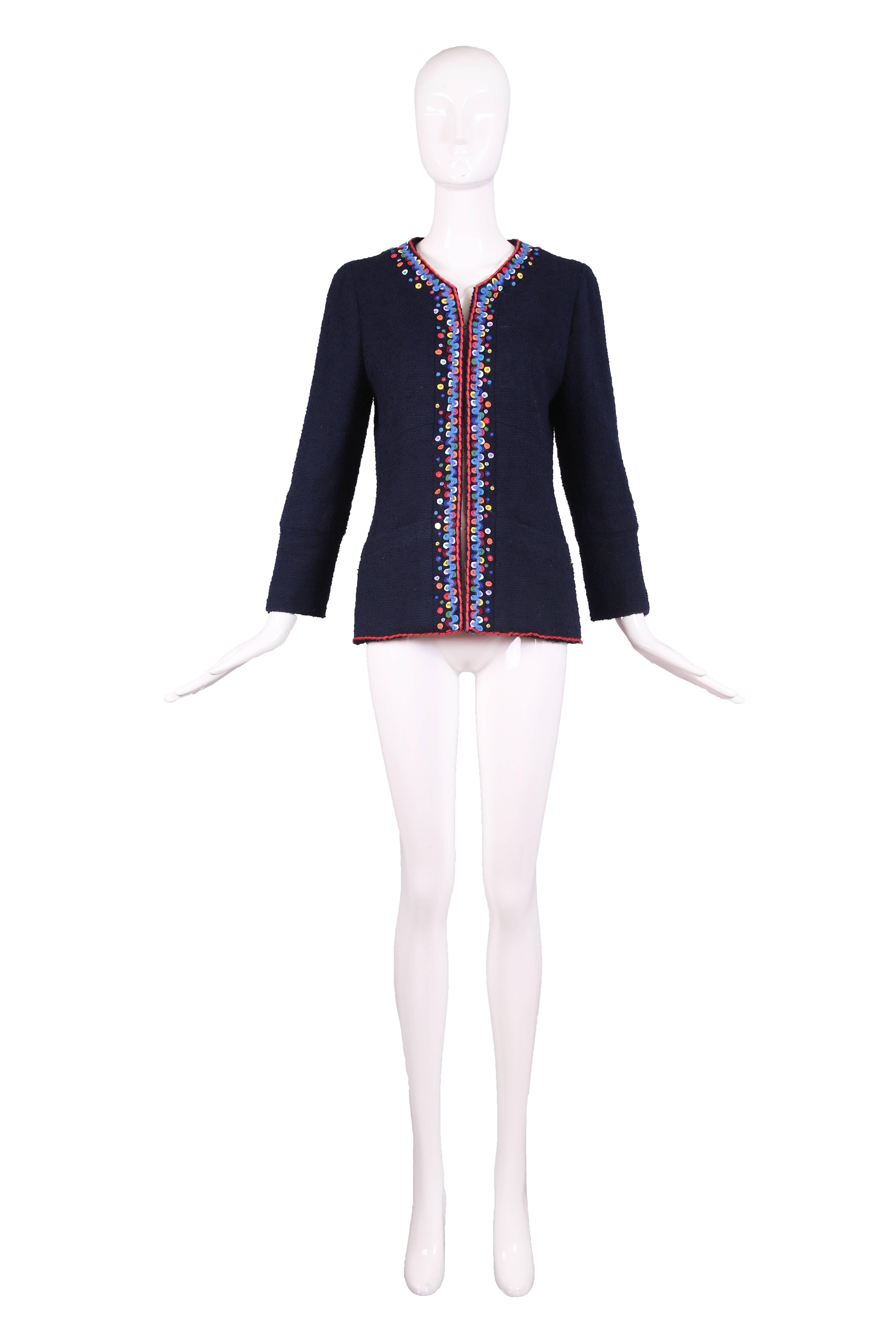 1997 Chanel navy blue wool boucle jacket featuring multi-colored felt and yarn whipstitched trim. Two hook and eye closures at bust. Two frontal square pockets with one metal CC logo button detail at left pocket. Fully lined in CC logo silk with