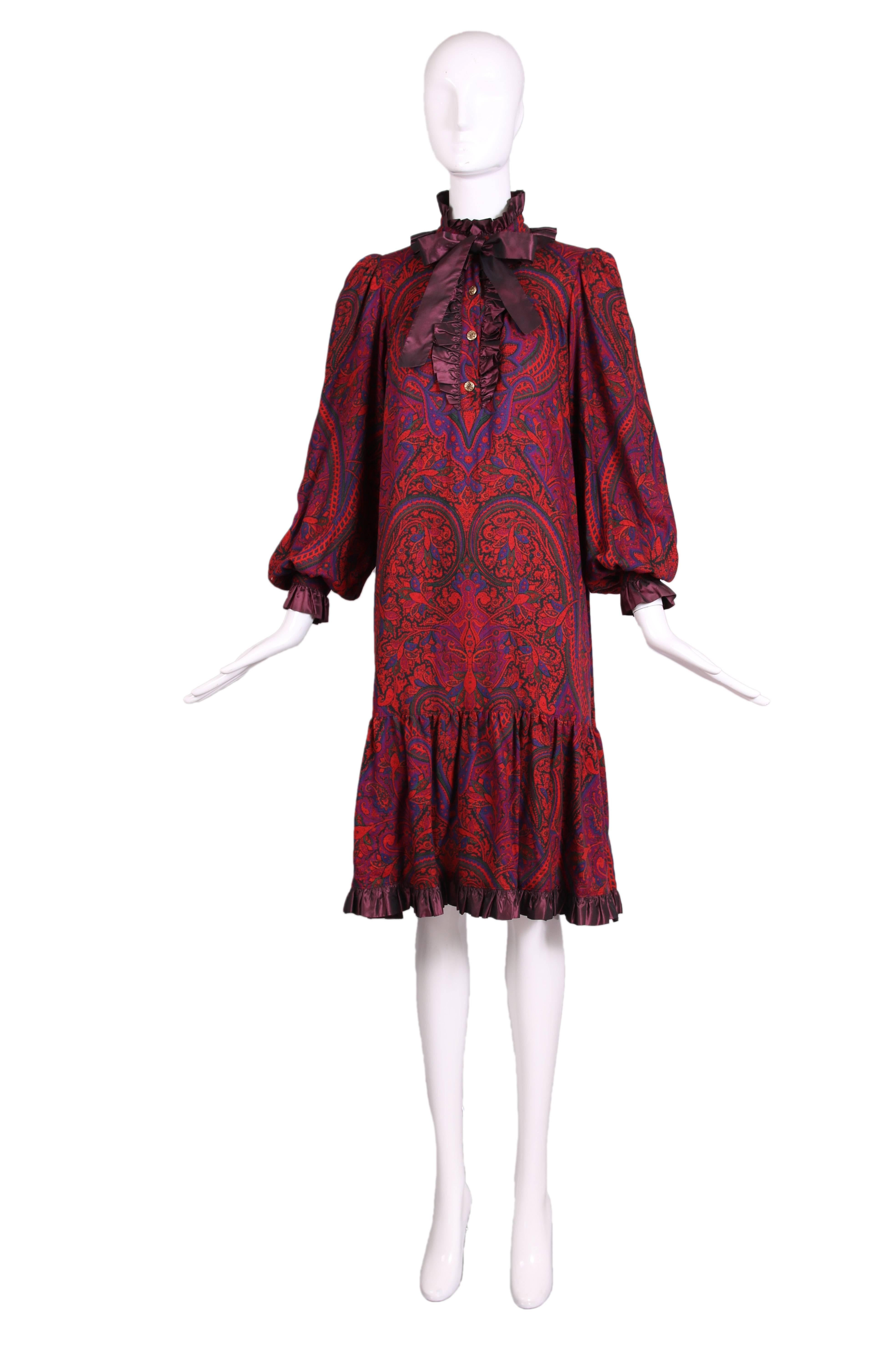 1970's Yves Saint Laurent light-weight wool paisley print smock dress in shades of purple, green, blue and orange-red with purple taffeta ruffled trim. Features metal paisley design buttons and hidden pockets at either side seam. In excellent