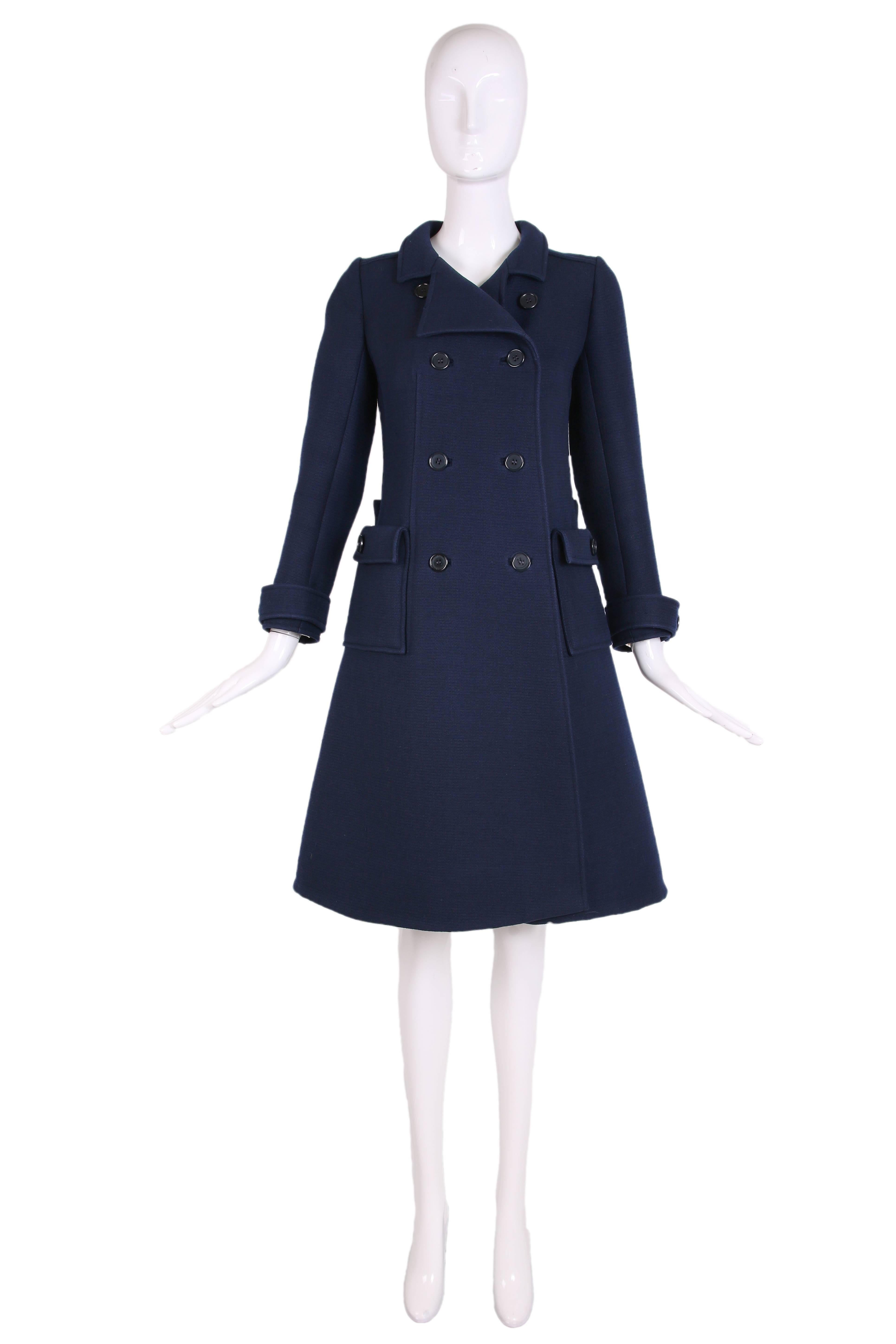 1960's Courreges for Bonwit Teller mod navy wool double-breasted coat. Fully lined with back bar belt and flap pockets. Courreges size 0. In very good to excellent condition with some faint yellow staining throughout the interior lining. Please