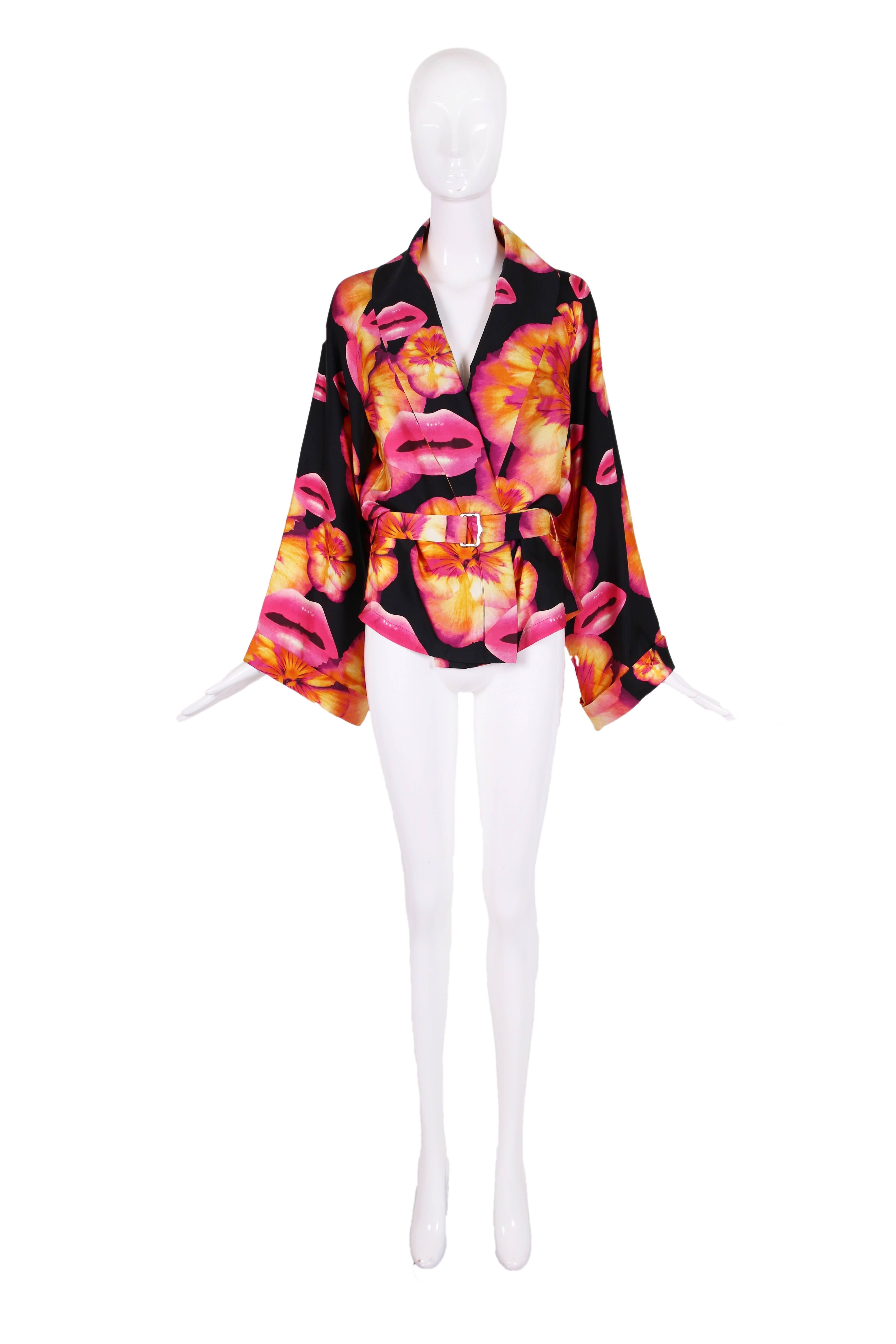 Christian Dior by John Galliano 100% silk pink, purple, yellow, orange and black techno lip and pansy print belted jacket or top in the style of a kimono. Features full sleeves, a lapel that transitions at the waist into parallel bands, belt loops