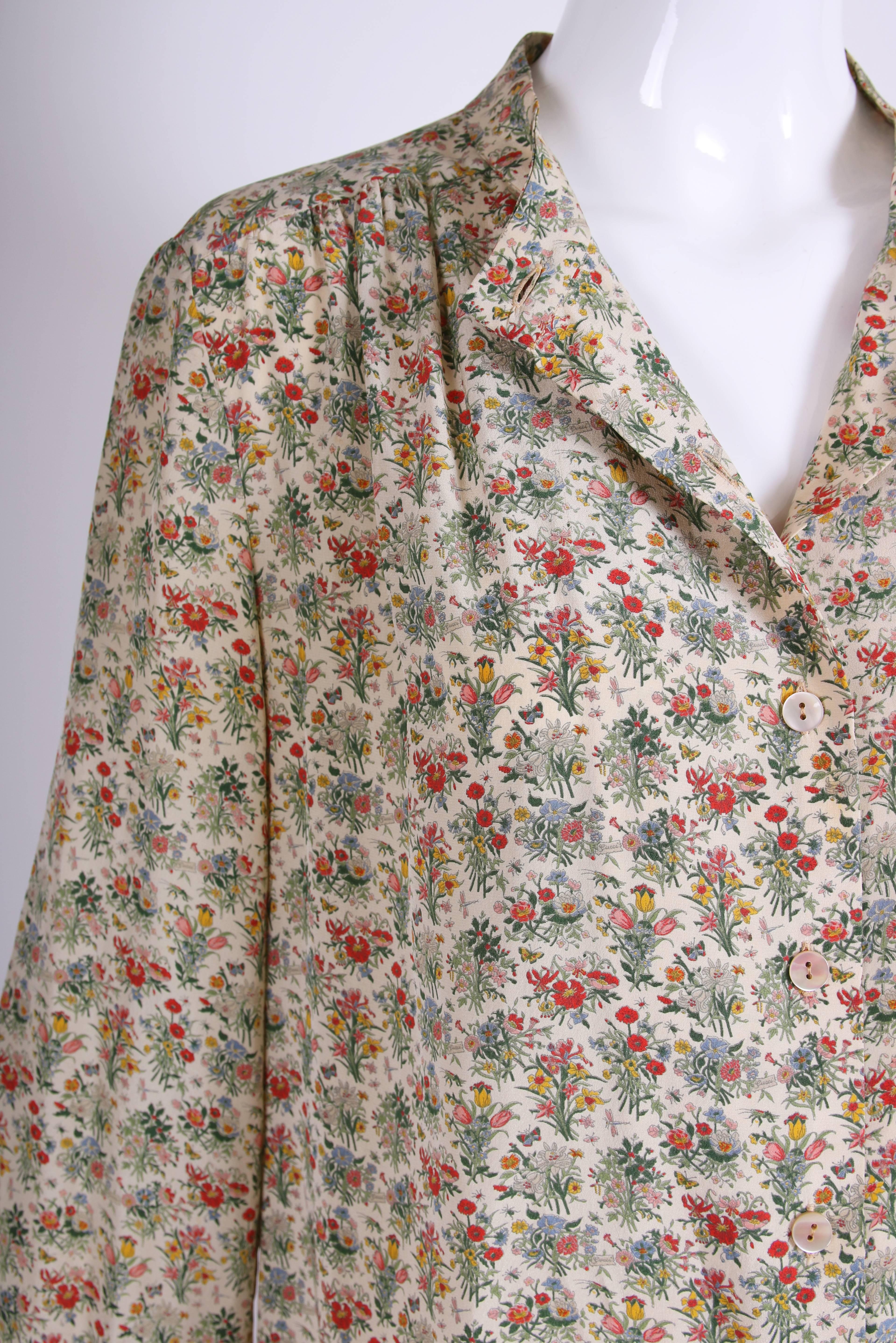 1970's Gucci silk long sleeved tunic style blouse featuring an Accornero print of flower bunches, bees, dragonflies and butterflies. With a low stand collar and slight gathers to the fabric at the front of the shoulders, the blouse features