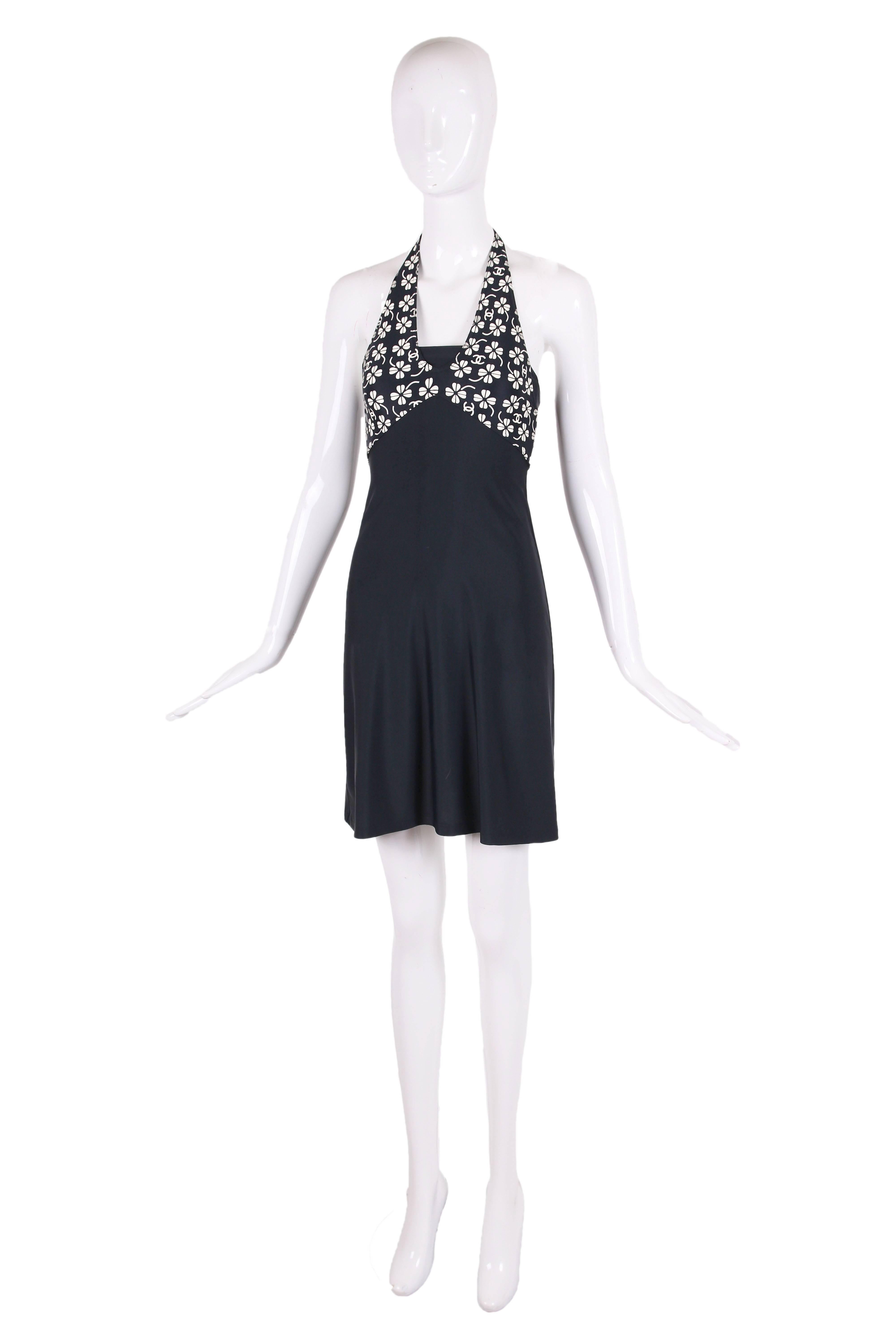 2001 Chanel navy blue nylon and spandex halter dress featuring cream-colored clover and CC logo print. The halter has an interior bandeau and a silver-toned CC logo clasp at back neck. In excellent condition. Size EU 34. 
MEASUREMENTS:
Bust -