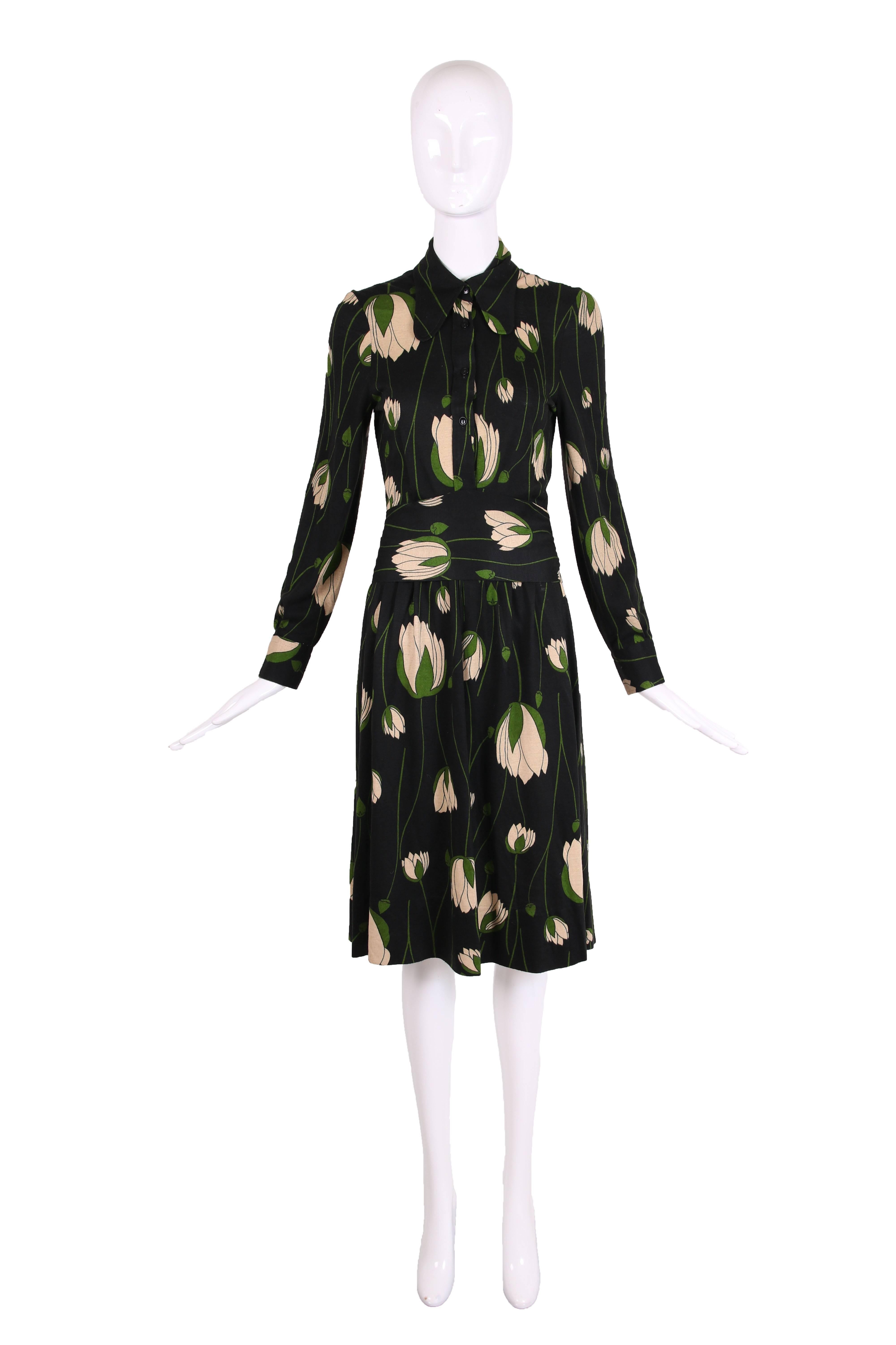 1970's Diane Von Furstenberg black stretch fabric dress with collar, long sleeves, four top buttons, and waist tie that wraps around back. Tulip print in cream and green. In excellent condition. Please consult measurements for size.