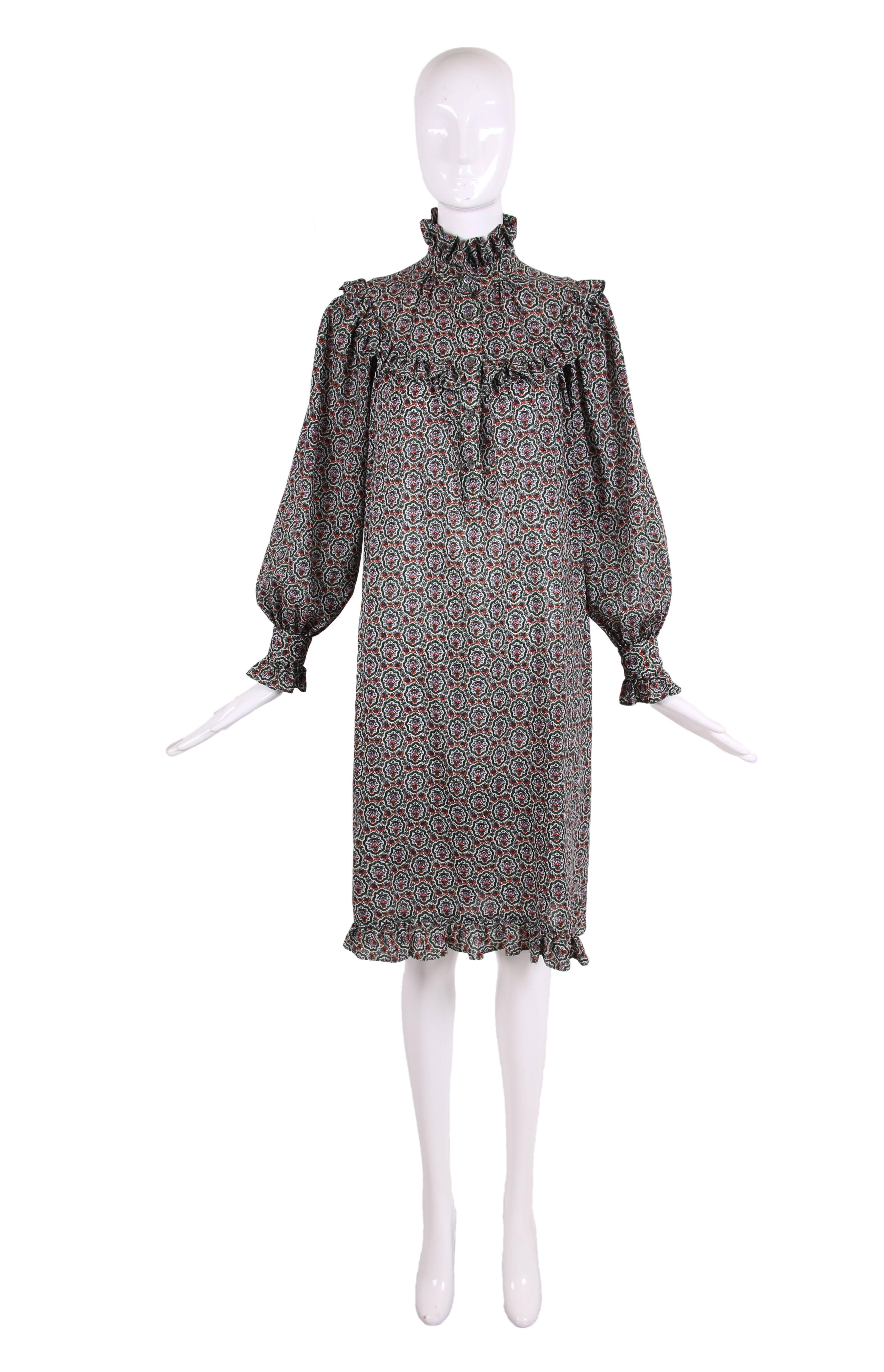 1970's Yves Saint Laurent classic peasant or smock dress in a light weight wool featuring a multi-colored floral print, hidden side pockets and ruffle trim at neck, smock edge, sleeve cuffs and hem. Button closures at center front bodice to the