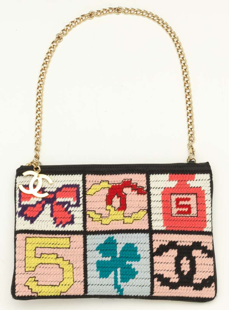 Iconic and hard-to-find Chanel needlepoint pochette featuring six sections with lucky symbols: a bow, the Chanel CC logo, Chanel No. 5 perfume bottle, a number 5, and a shamrock. Top zip closure is decorated with gold tone interlocking CC logo