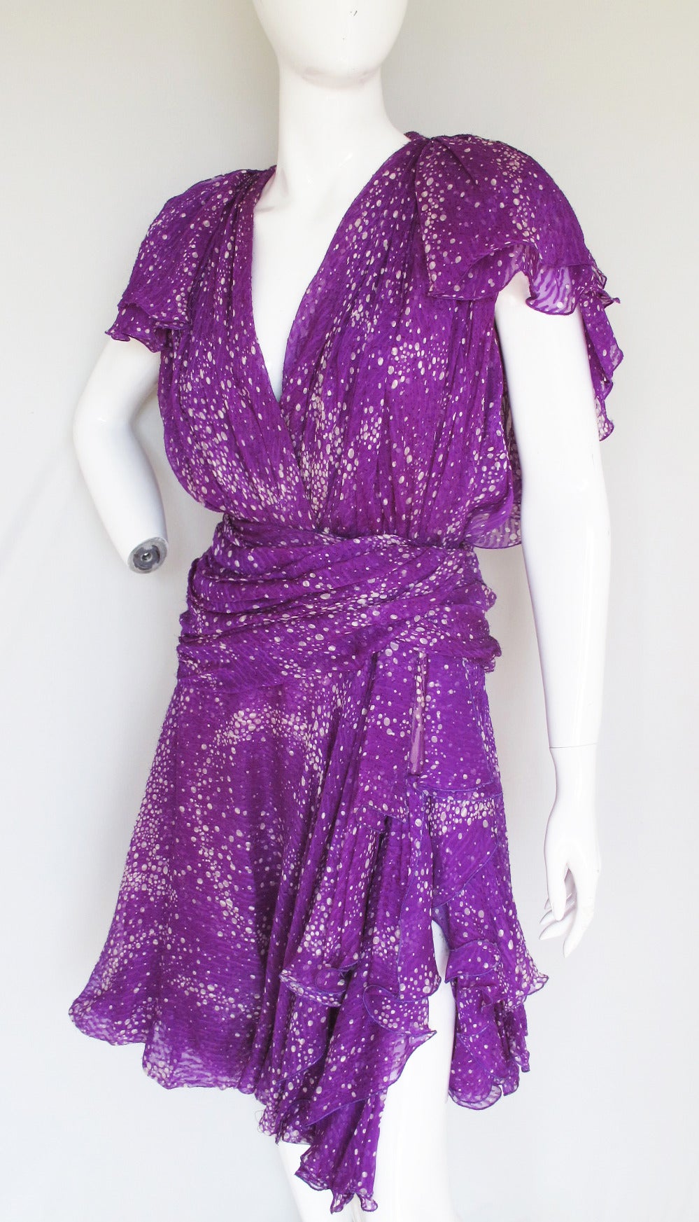 A Jacqueline de Ribes multi-layered silk chiffon cocktail dress with plunge neckline, flounced sleeves, tiered side slit and bright purple chiffon fabric printed with a pattern of swirling gray and white circles. The bodice front is made from a