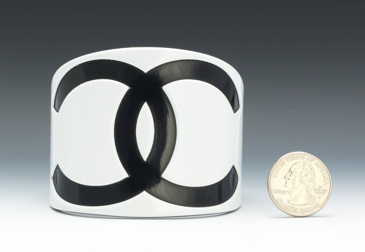 A wide Chanel white resin cuff with the iconic black interlocking CC logo. Black on the inside. 
