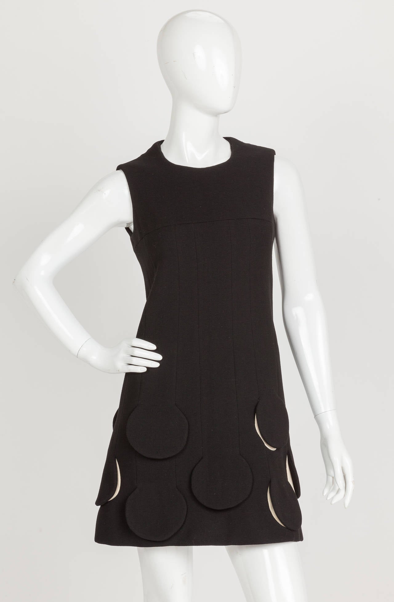 Circa 1967 - Pierre Cardin 'Rocket Dress' - a fitted black wool sleeveless dress that features  Space Age circle cutout/flaps at the hem. Lined entirely in silk and zippers to the left of center back In excellent condition. No size or fabric tag. My