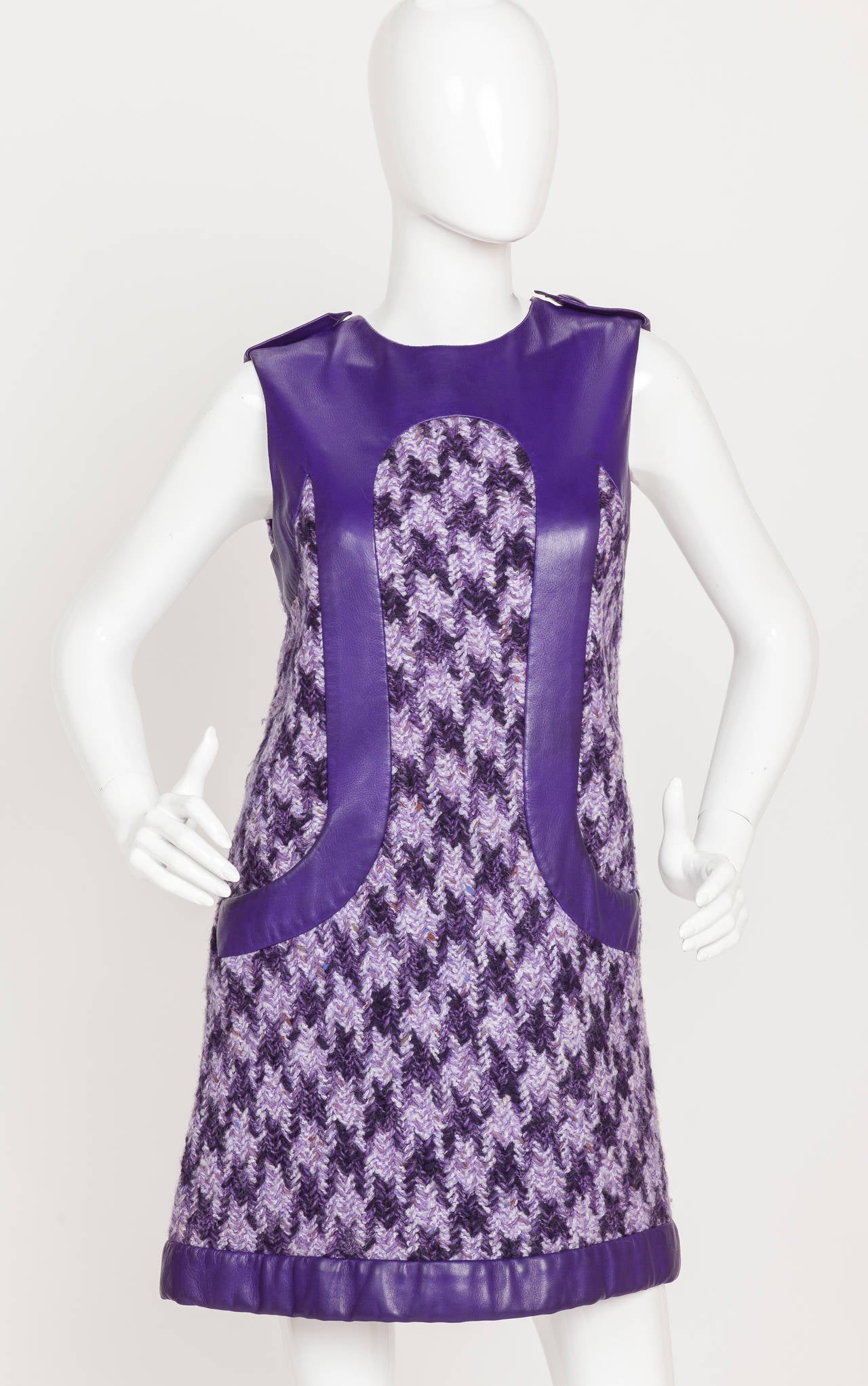 A rare 1968 Pierre Cardin haute couture mini dress made of oversize herringbone wool tweed with supple purple leather inserts at the neck, bust, hem and bodice front. Features hidden pockets at the termination of the curved frontal leather bands.